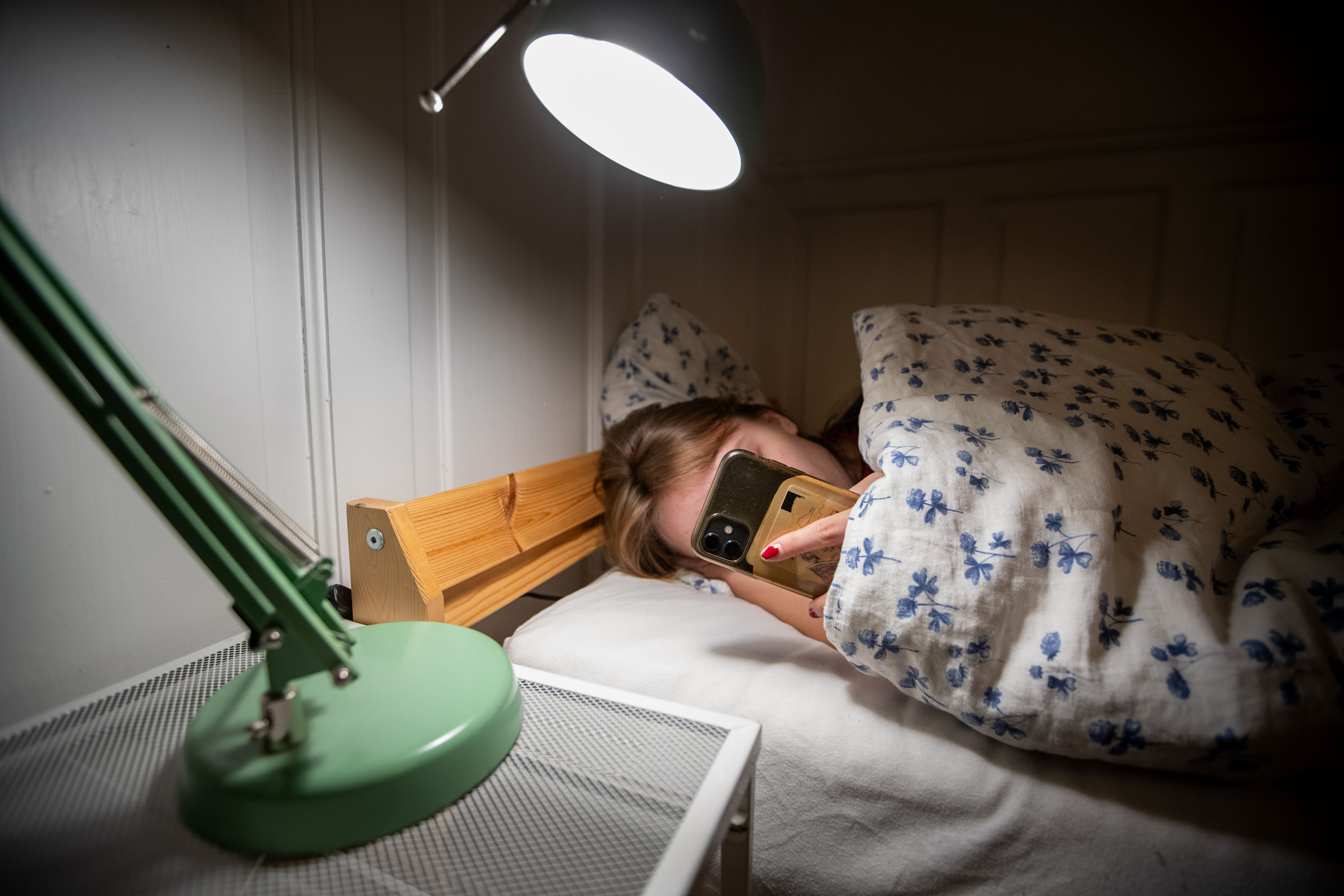 bilde av kvinne i sengen med mobil