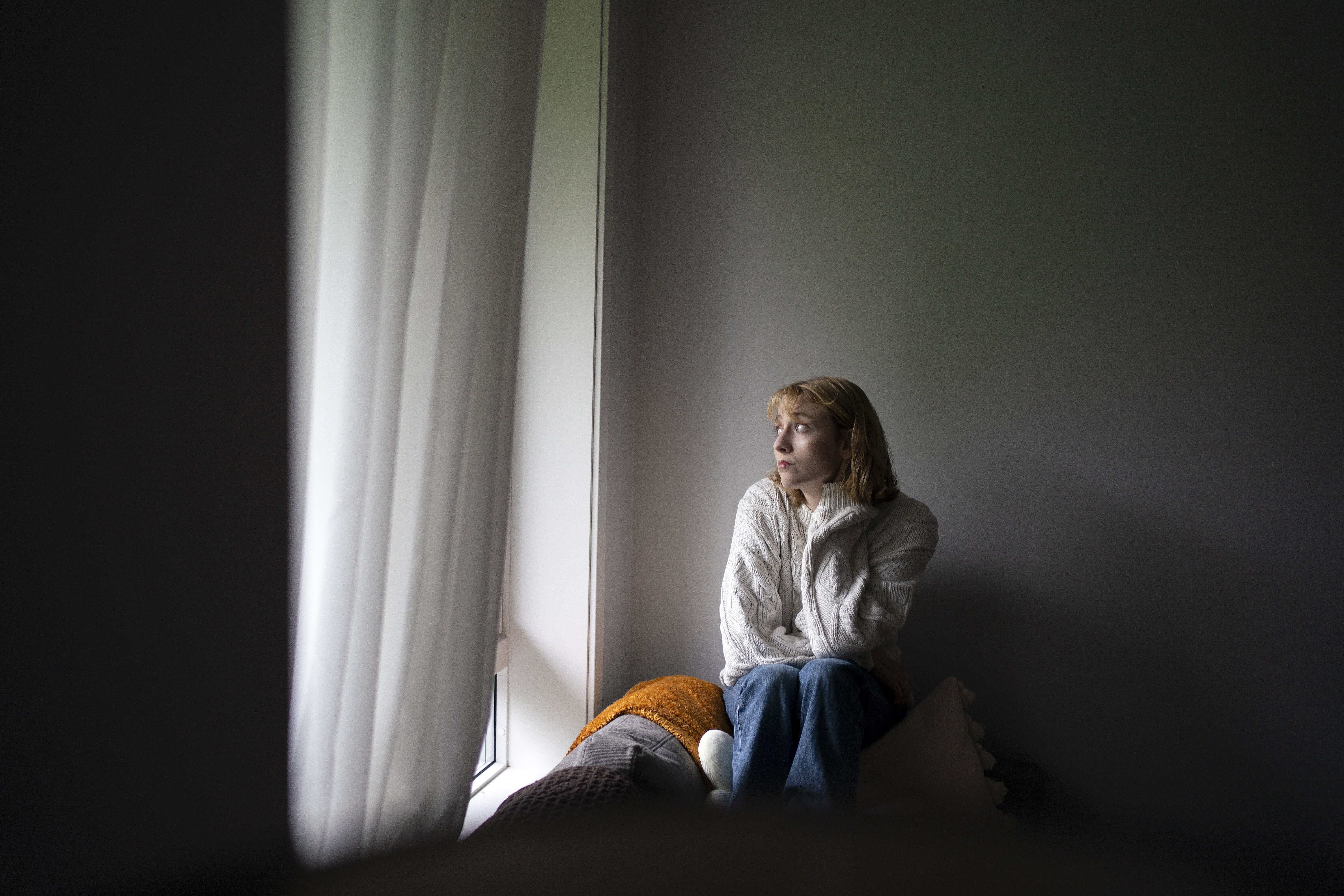 Bildet viser en kvinne som sitter ved et vindu.