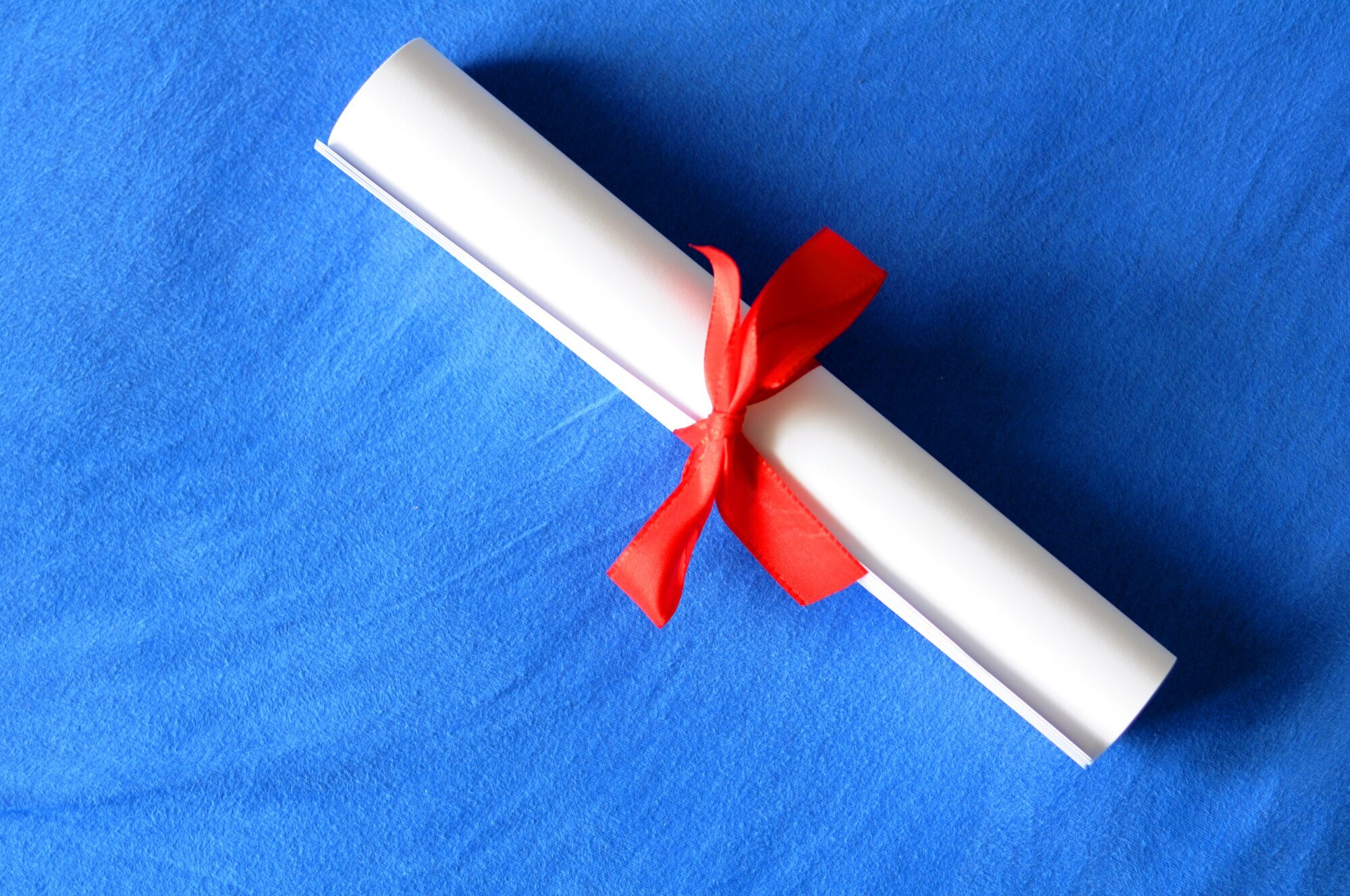 Sammenrullet diplom med rødt sløyfebånd rundt Sammenrullet diplom med rødt sløyfebånd rundt