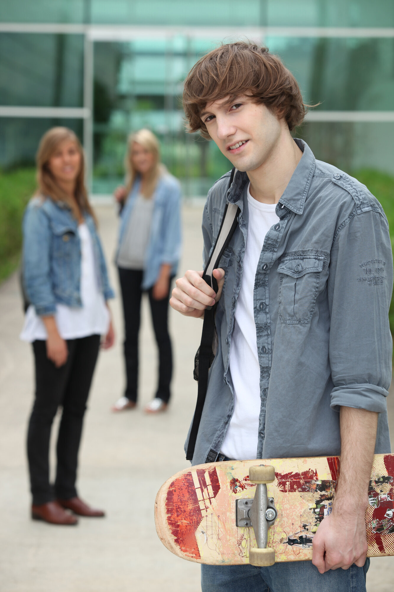 Bilde av en ung mann med skolesekk, og to unge kvinner i bakgrunnen. Bilde av en ung mann med skolesekk, og to unge kvinner i bakgrunnen.