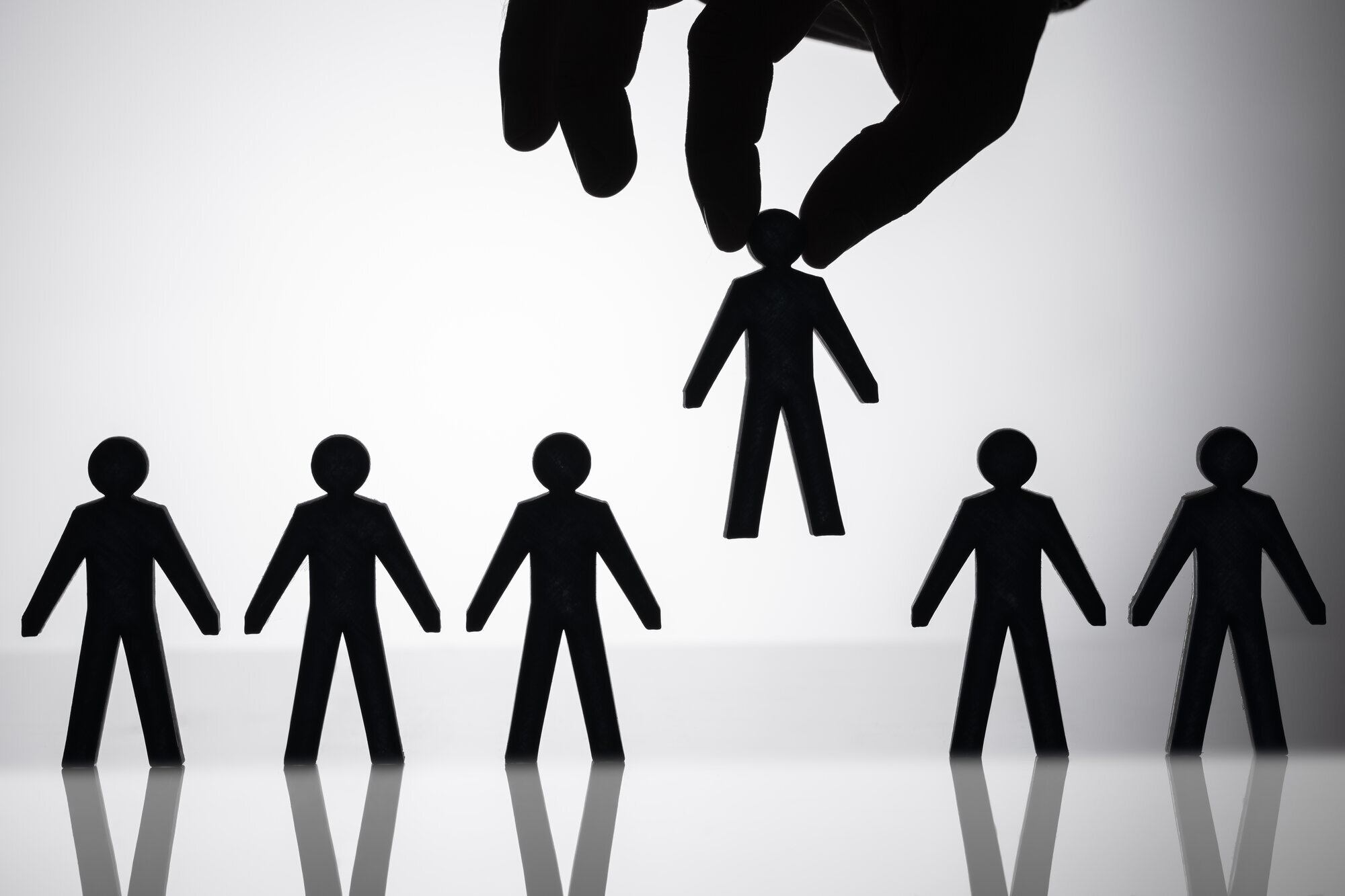 Sykepleiermangel og ufaglærte Bildet viser mange mennesker som står på rekke og rad og en hånd som plukker opp et av menneskene