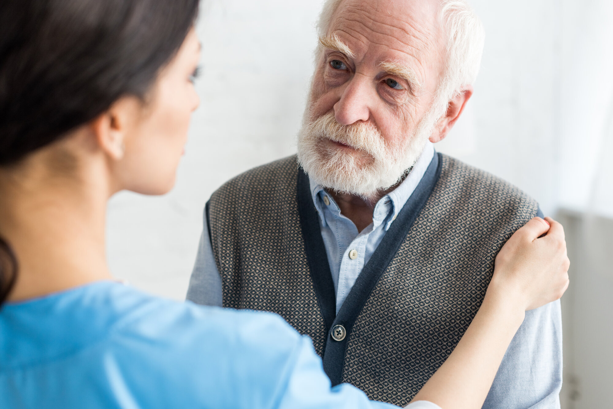 Pleier legger hånden på armen til eldre mann