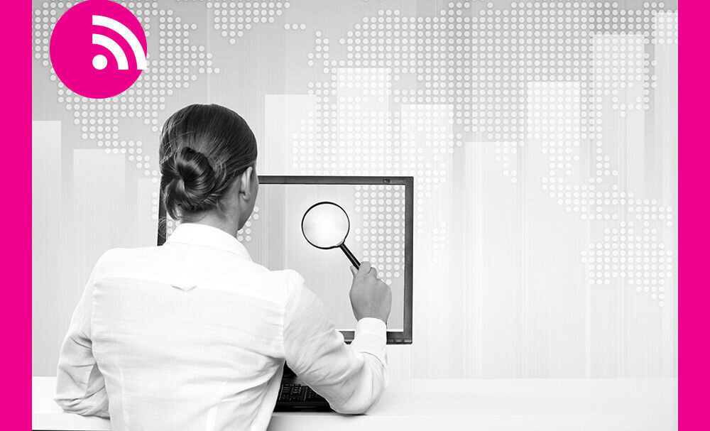 Dame med forstørrelsesglass foran PC Bildet viser ryggen på en dame som holder et forstørrelsesglass foran en PC-skjerm