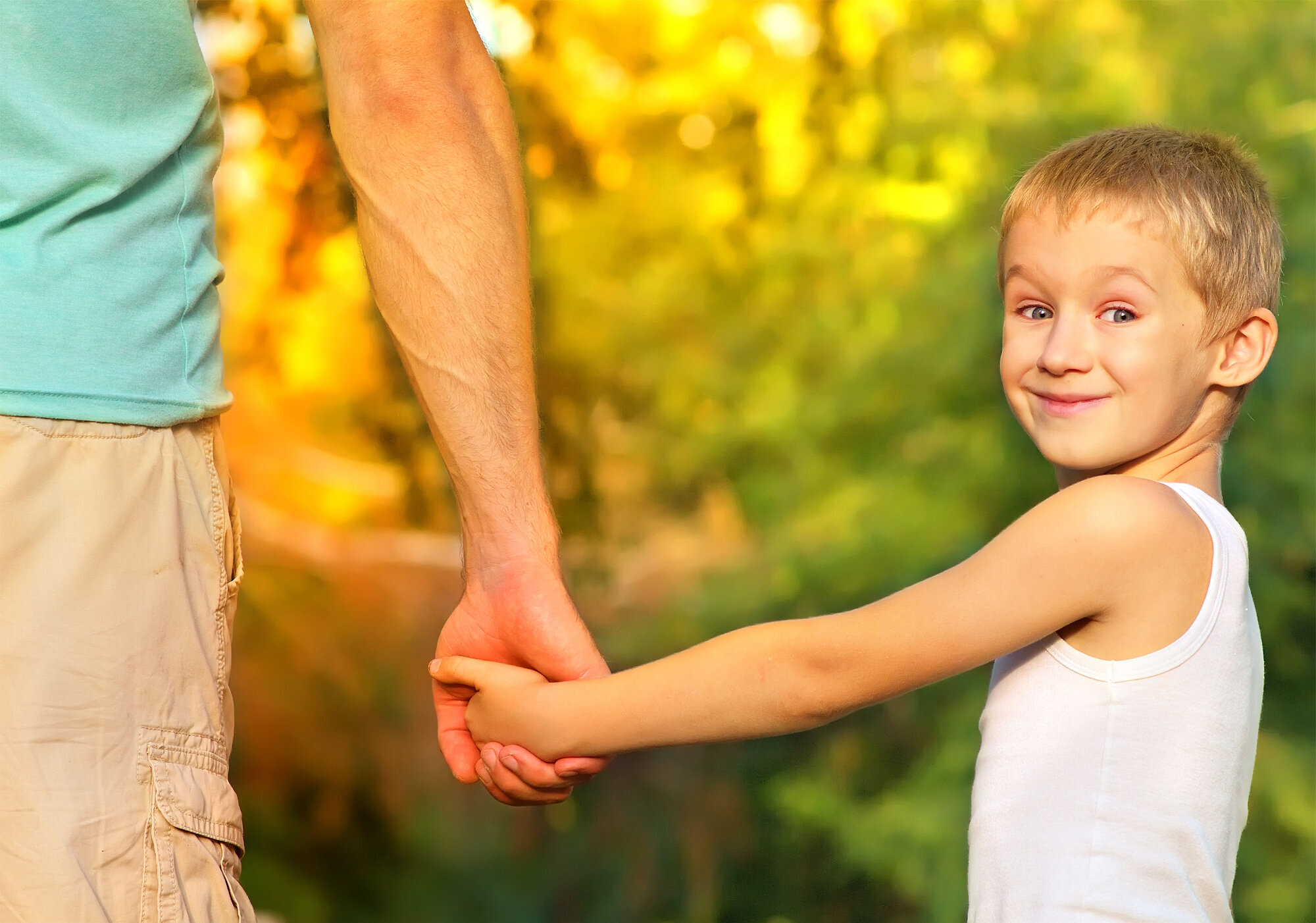 Sønn og far Bildet viser en smilende gutt som holder sin far i hånden