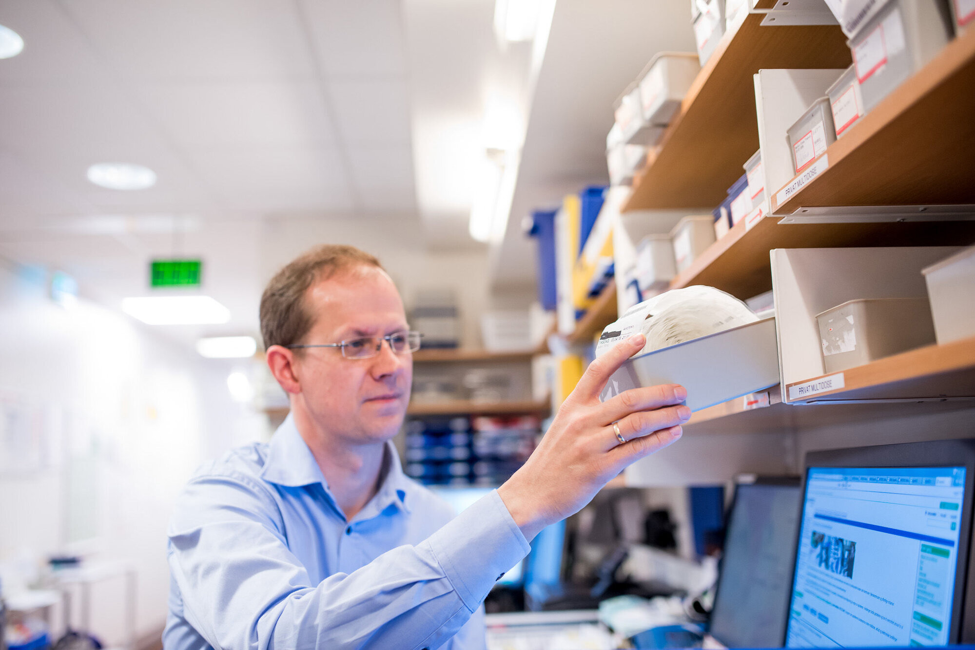 Apoteker med multidoserull Bildet viser en apoteker som henter en multidoserull i hyllen