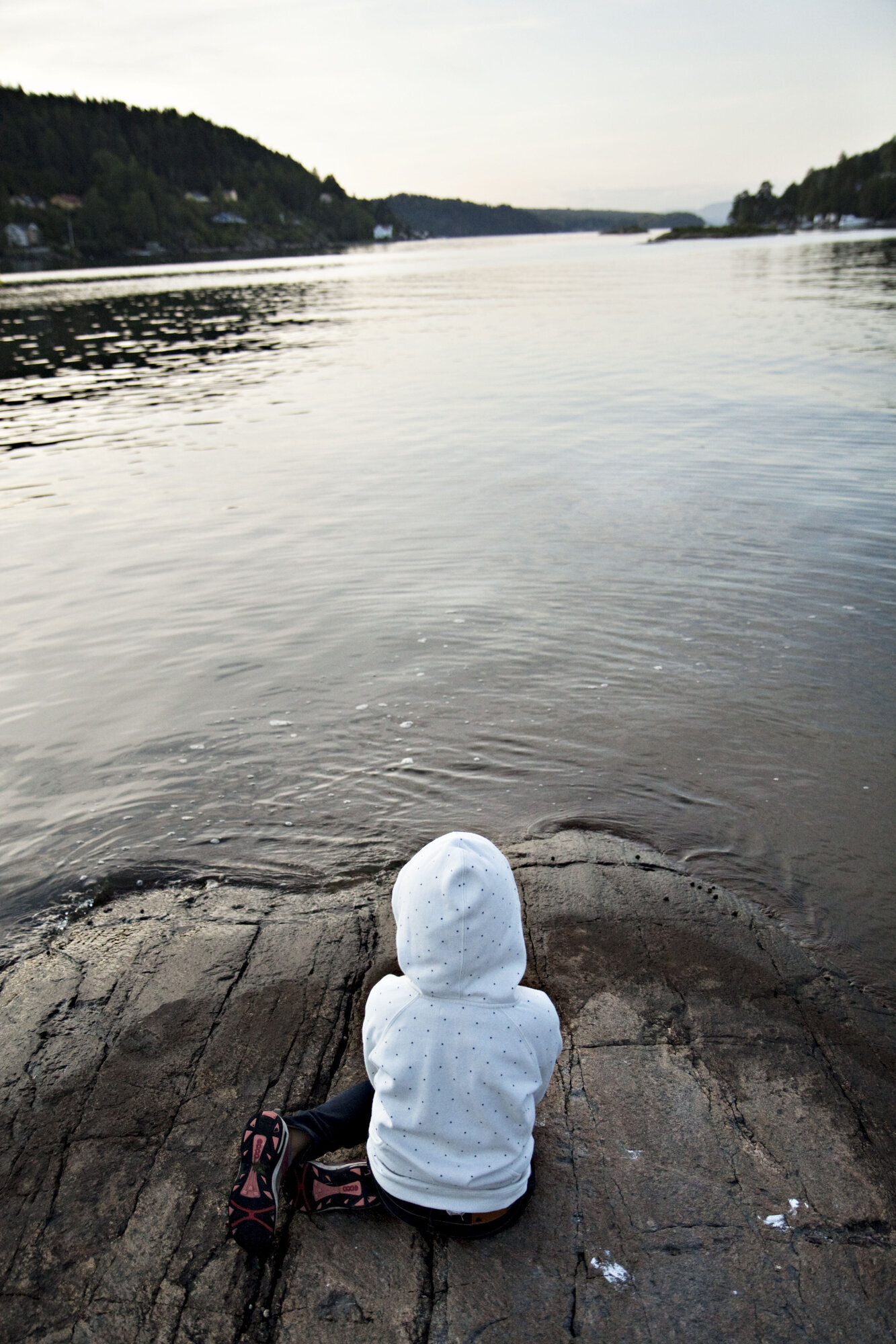 barn med ryggen til ser utover sjøen Bildet viser barn med ryggen til ved sjø