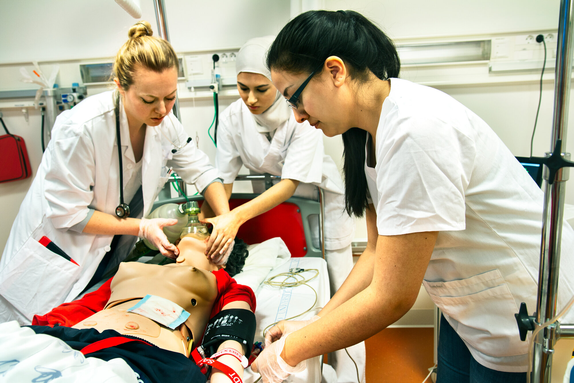 Sykepleier- og legestudenter simulerer en akuttsituasjon. Sykepleier- og legestudenter øver på en akuttsituasjon med en dukke i sykesengen.