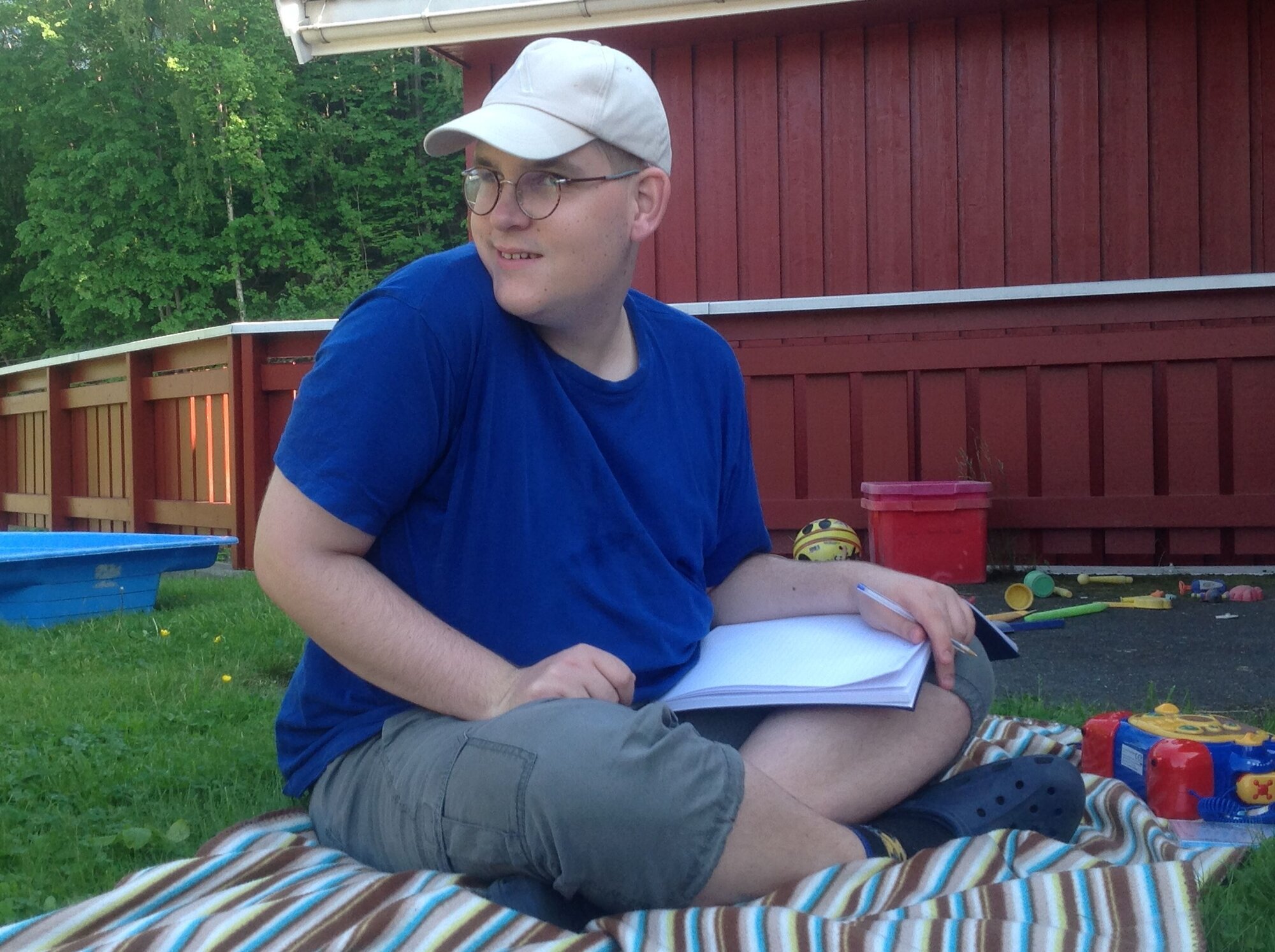 Bilde av Alexander som sitter på gresset med en bok i fanget Bilde av Alexander som sitter på gresset med en bok i fanget