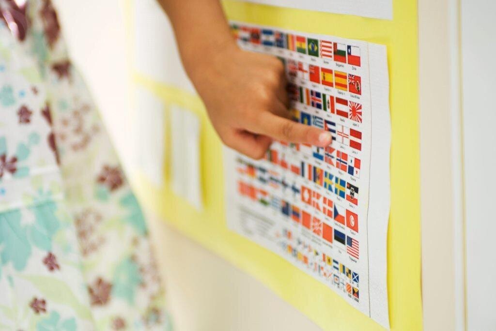 Etisk rekruttering av sykepleiere er først og fremst på dagsorden hos NSF fordi helsepersonell er sårt savnet i mange fattige land og fordi rike land rekrutterer helsepersonell fra disse landene, heter det i en rapport fra forbundet. Bildet viser en kvinnehånd som peker på en plakat med ulike nasjonalflagg.