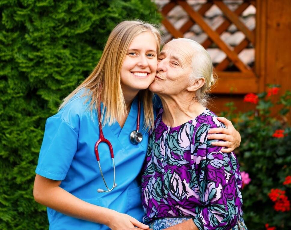 Eldreomsorg, proriteringsrådet, sykehjemsmedisin, sykehjem Bildet viser en ung lege som kysses på kinnet av en eldre pasient.