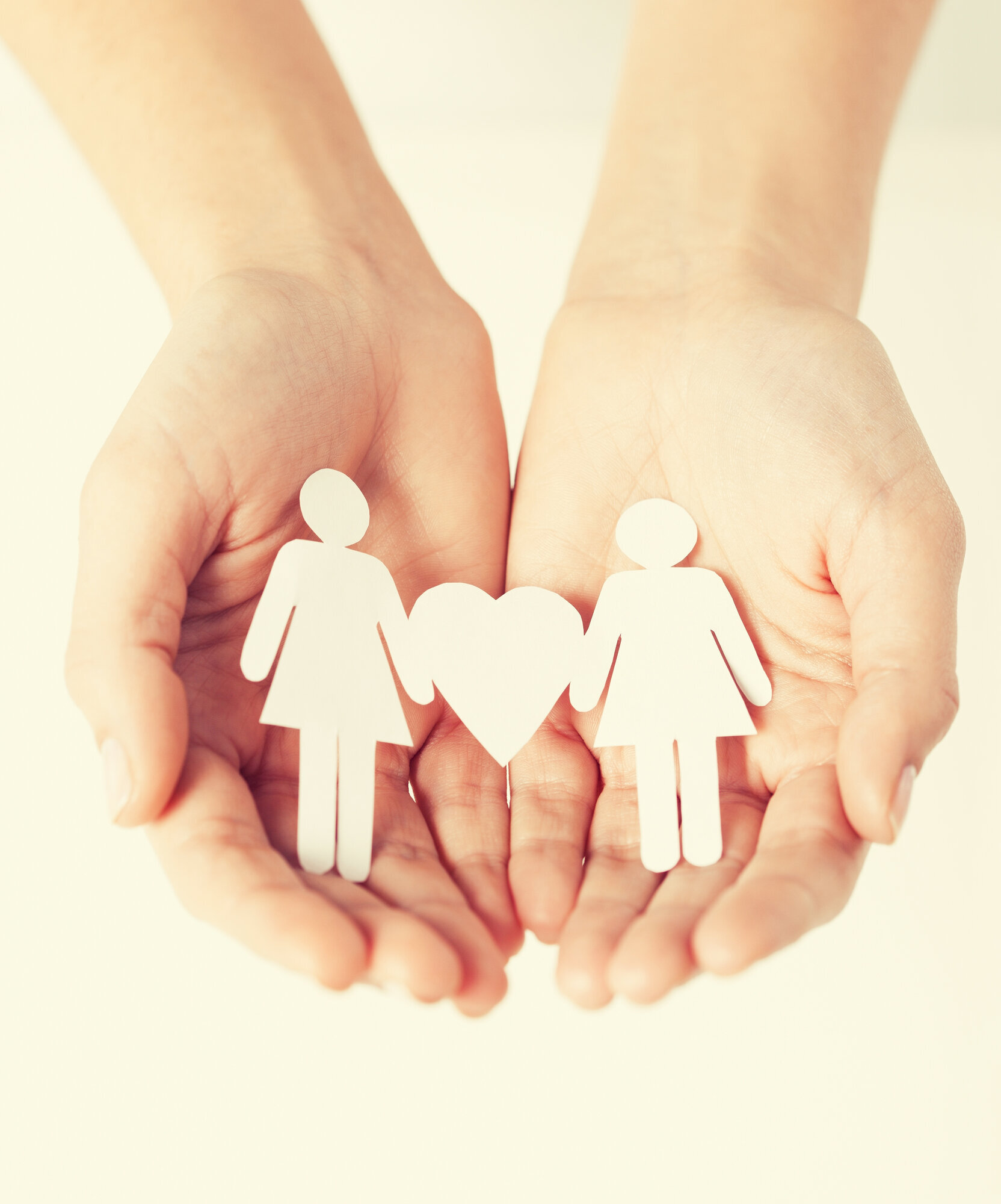 medmor Bildet viser to hender som holder papirdukker av to kvinner med et hjerte mellom seg.