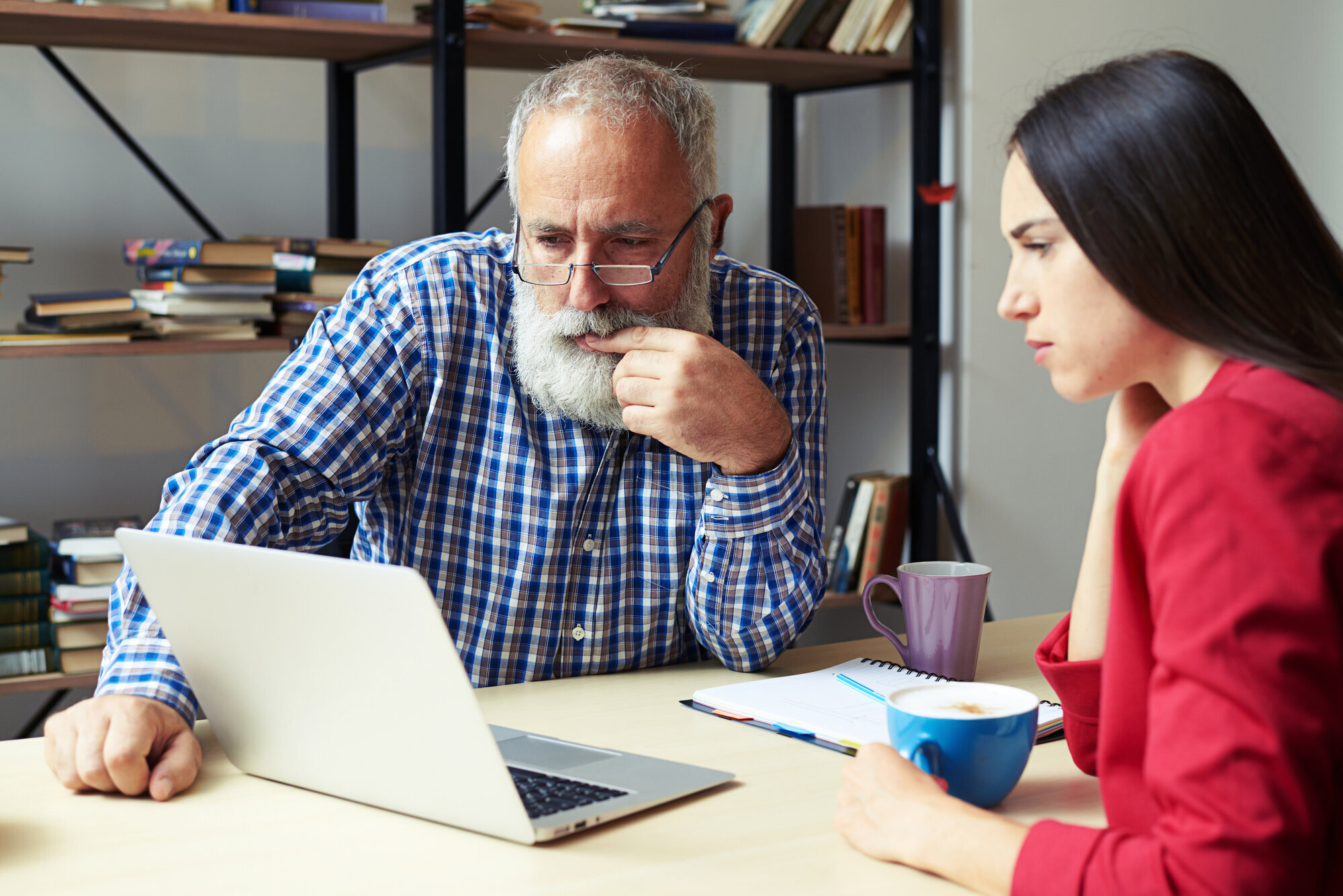 Ung jente og eldre mann ser på en PC Ung jente viser en eldre mann noe på PC-en sin på et kontor