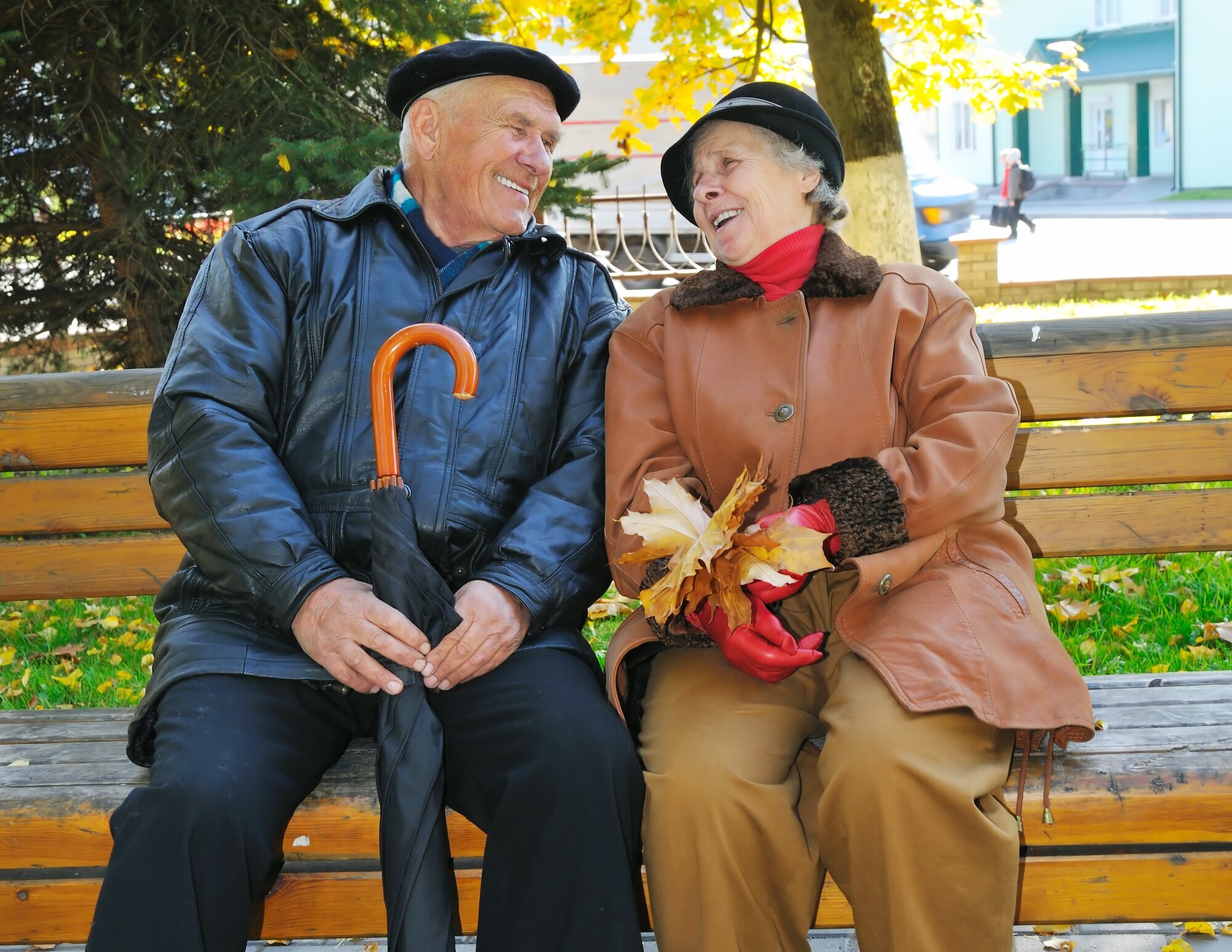 Eldre, alderdom, ensomhet Bildet viser to eldre mennesker som sitter på en benk og ler.