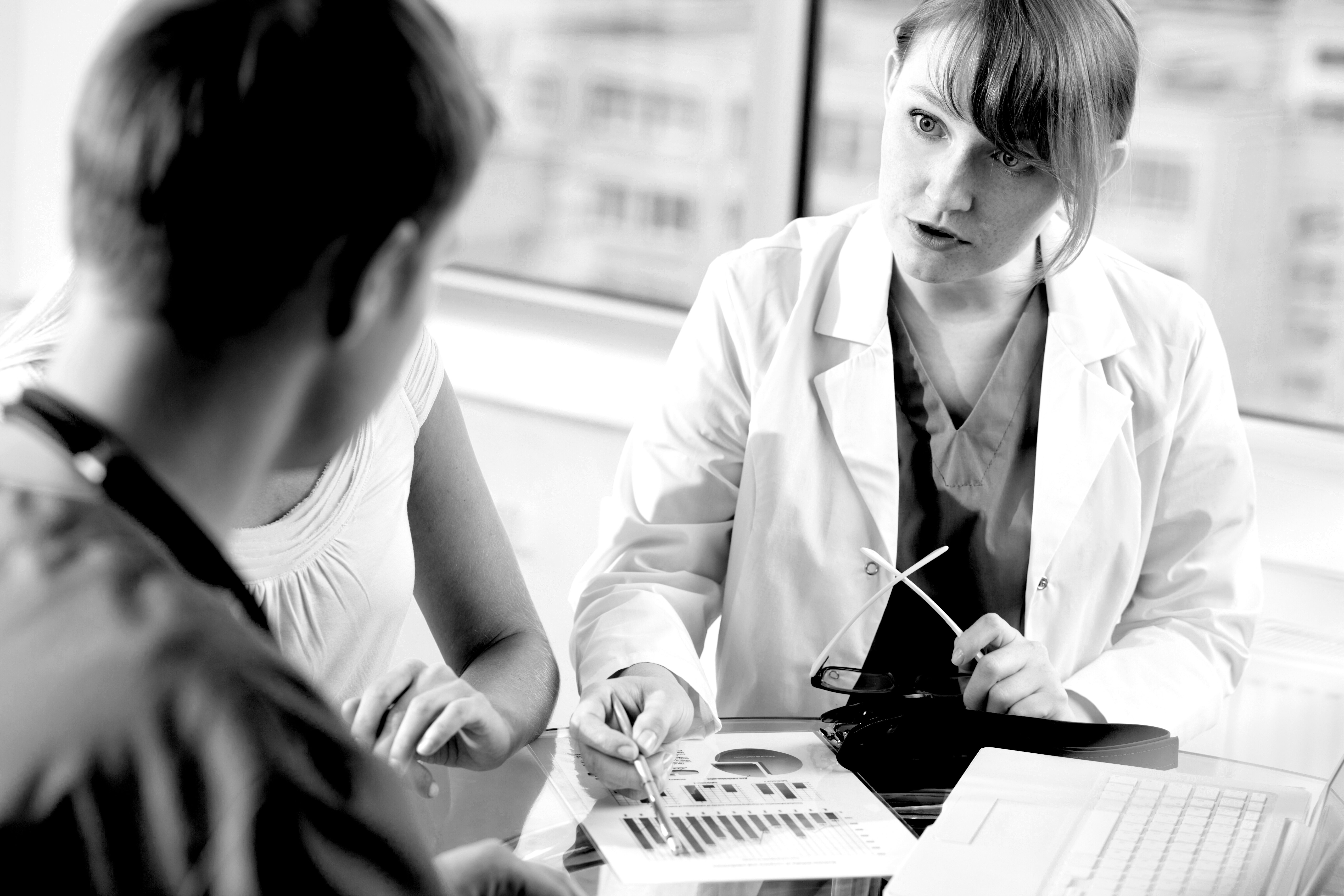 Undervisning, simulering, kommunikasjonskurs Bildet viser ei dame i hvit frakk som viser to personer et ark med et diagram på.