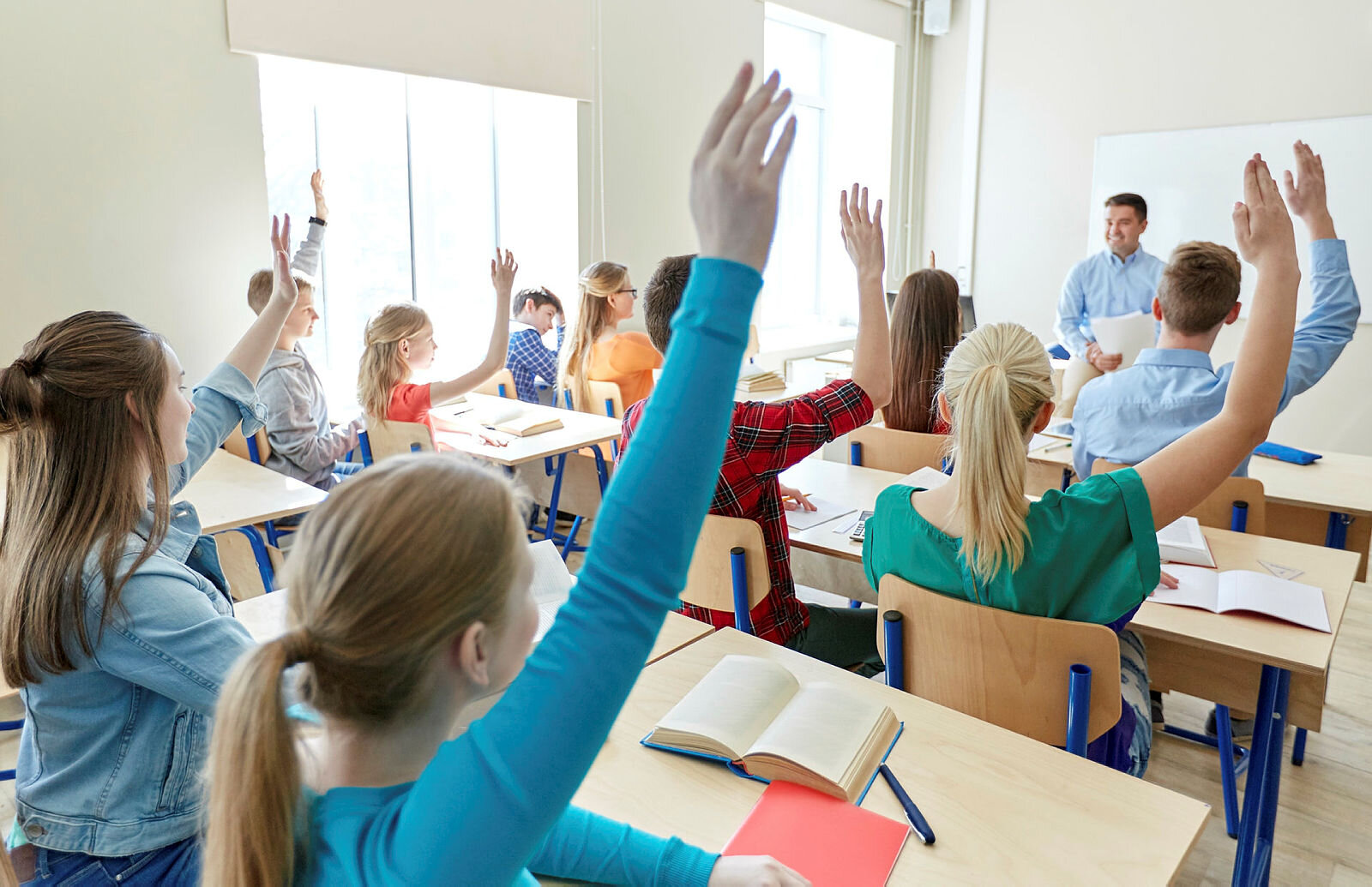 Elever i videregående skole Bildet viser elever i et klasserom som rekker opp hånden.
