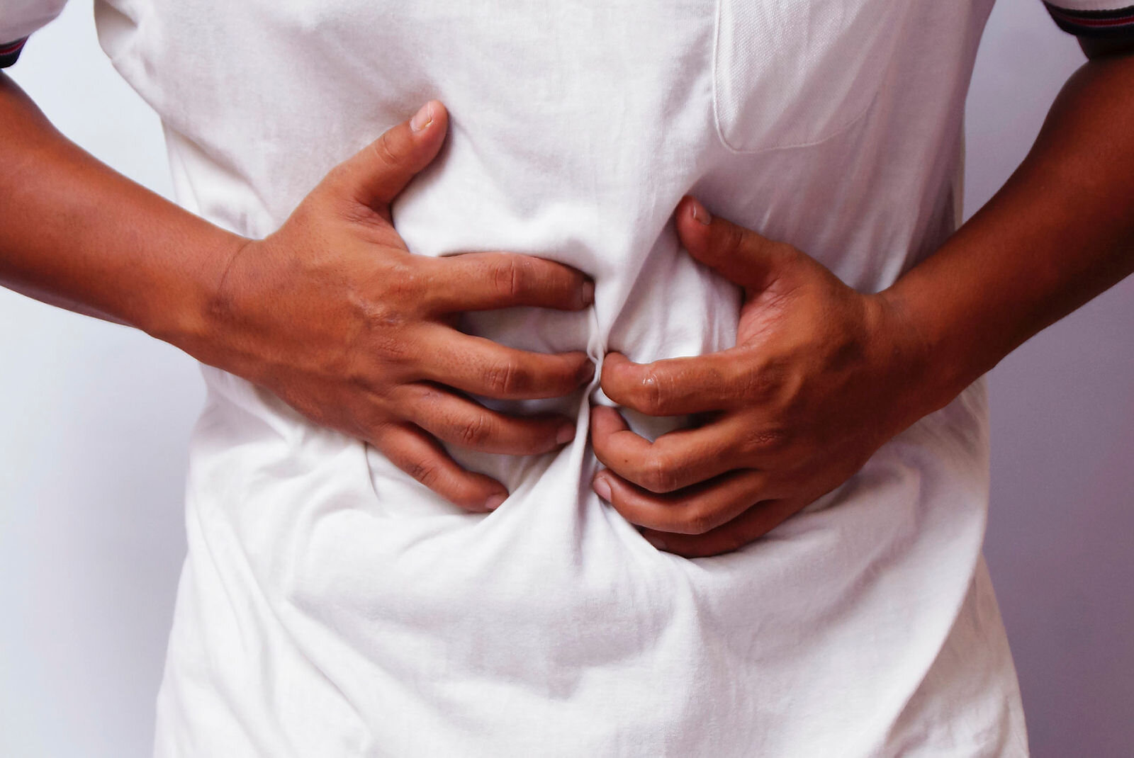 Bildet viser et menneske som holder seg på magen.