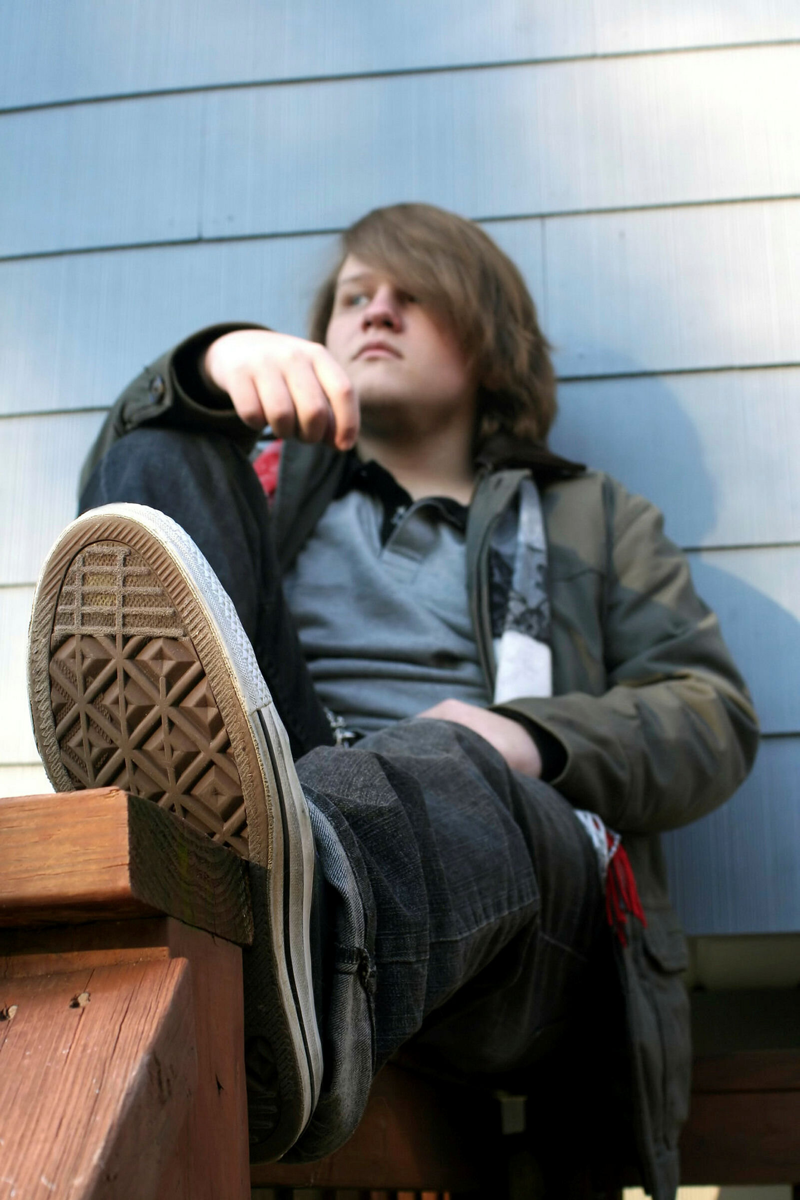 Tenåringsgutt sitter henslengt på en rekkverk.