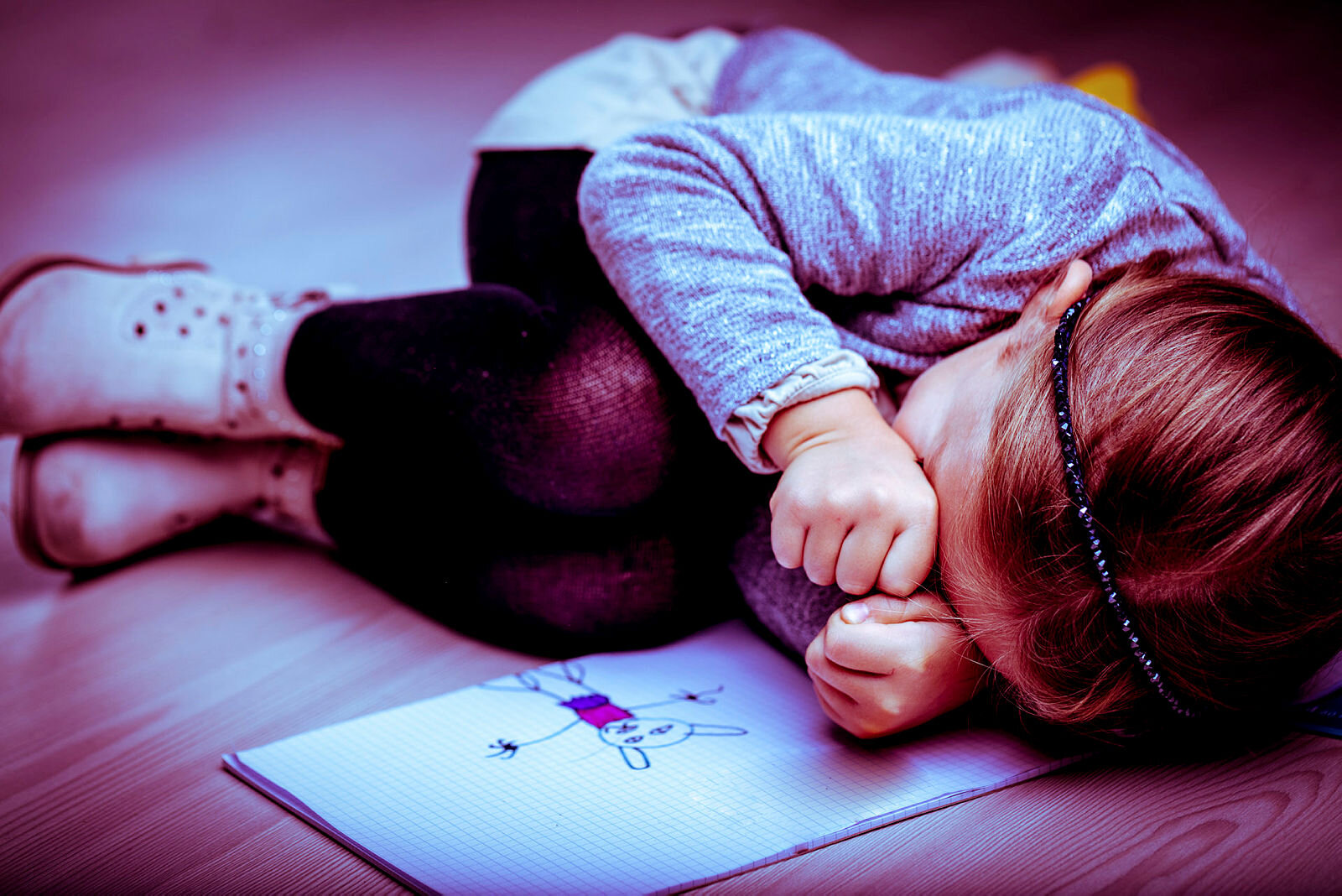 Gråtende jente Bildet viser en liten jente i fosterstilling ved siden av en tegning