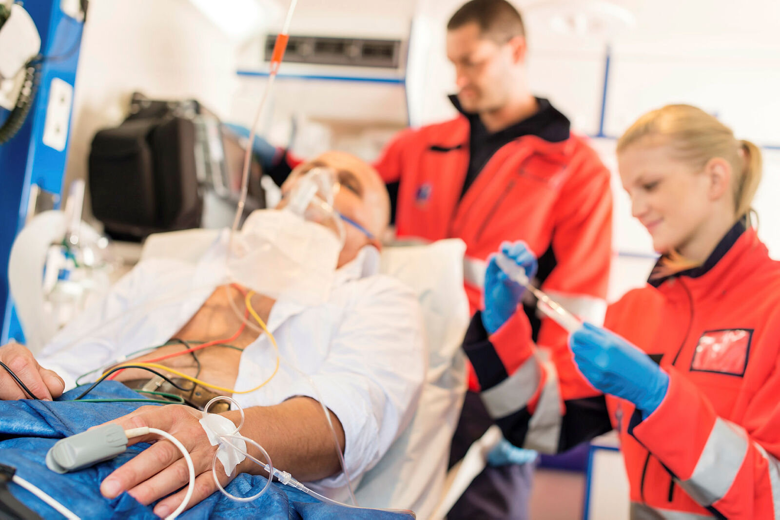 Behandling i ambulansen Bildet viser en pasient som blir behandlet i en ambulanse av to ambulansepersonell.