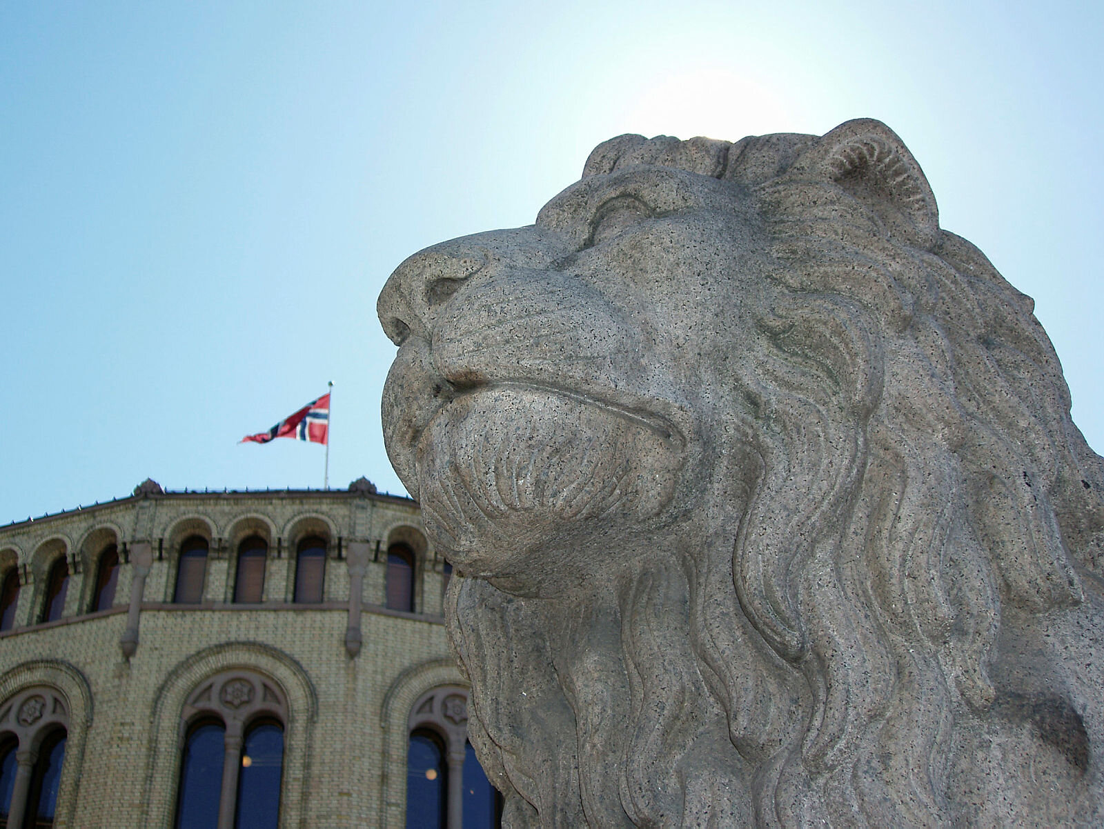 Bildet viser Stortinget og den ene løvestatuen utenfor.