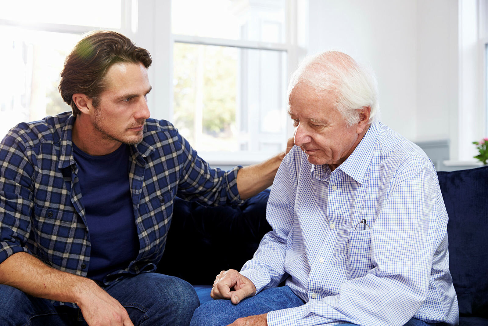 Bildet viser en sønn som snakker med en eldre, syk og nedfor far. Han holder armen trøstende på skulderen til faren.