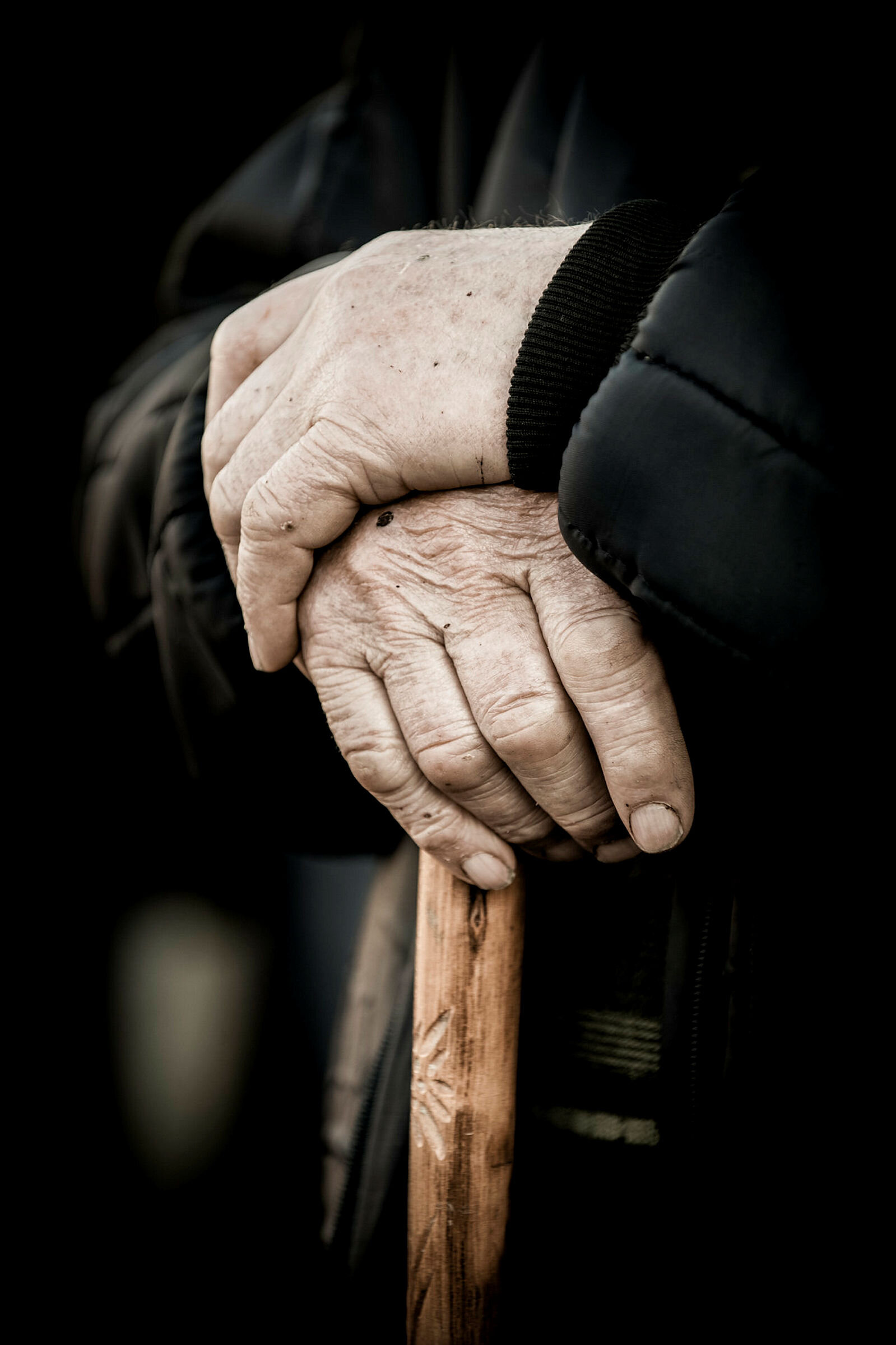Nærbilde av eldre hender på en stokk