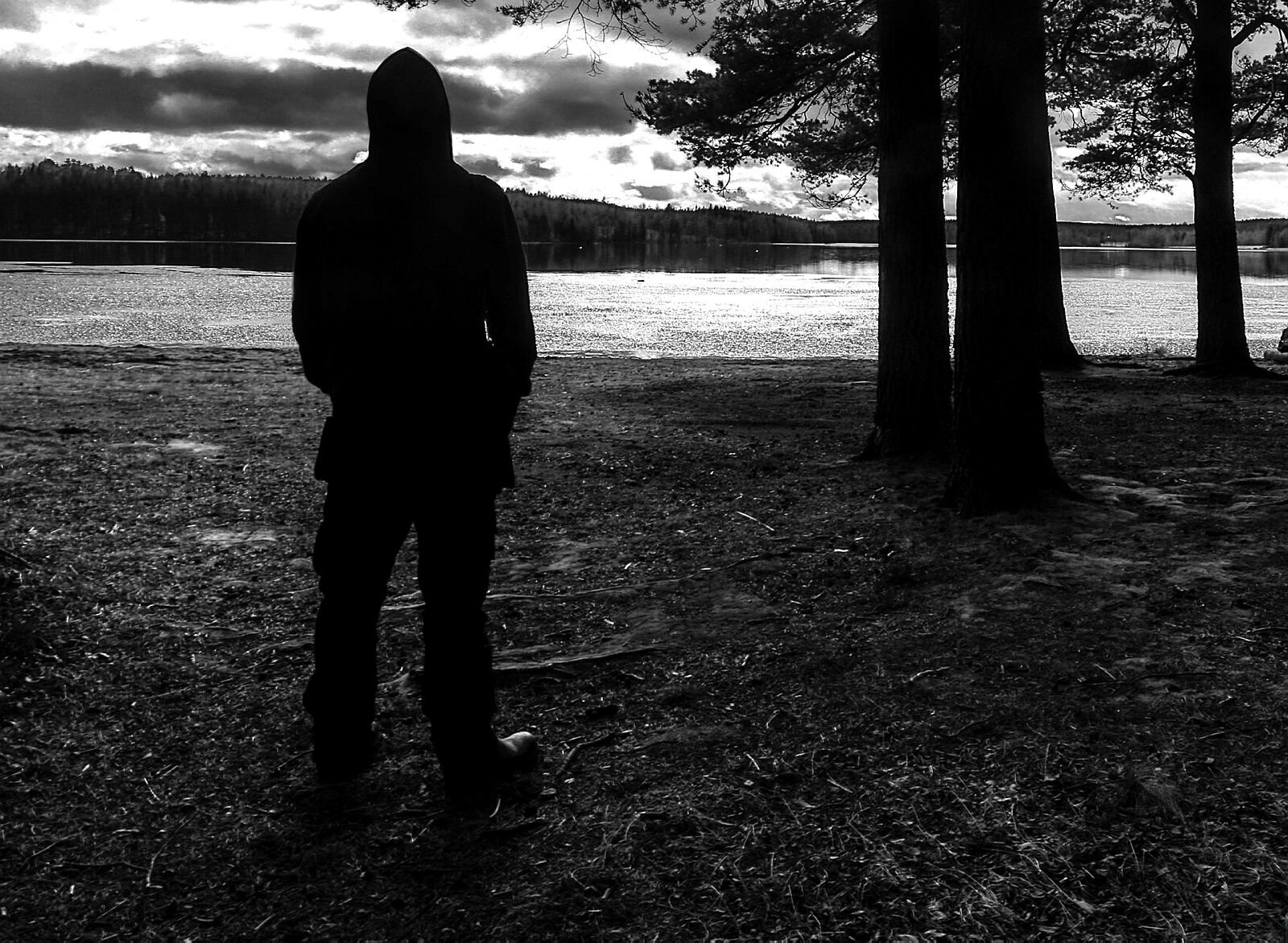 Viser anonym skikkelse som står og ser ut over et vann.