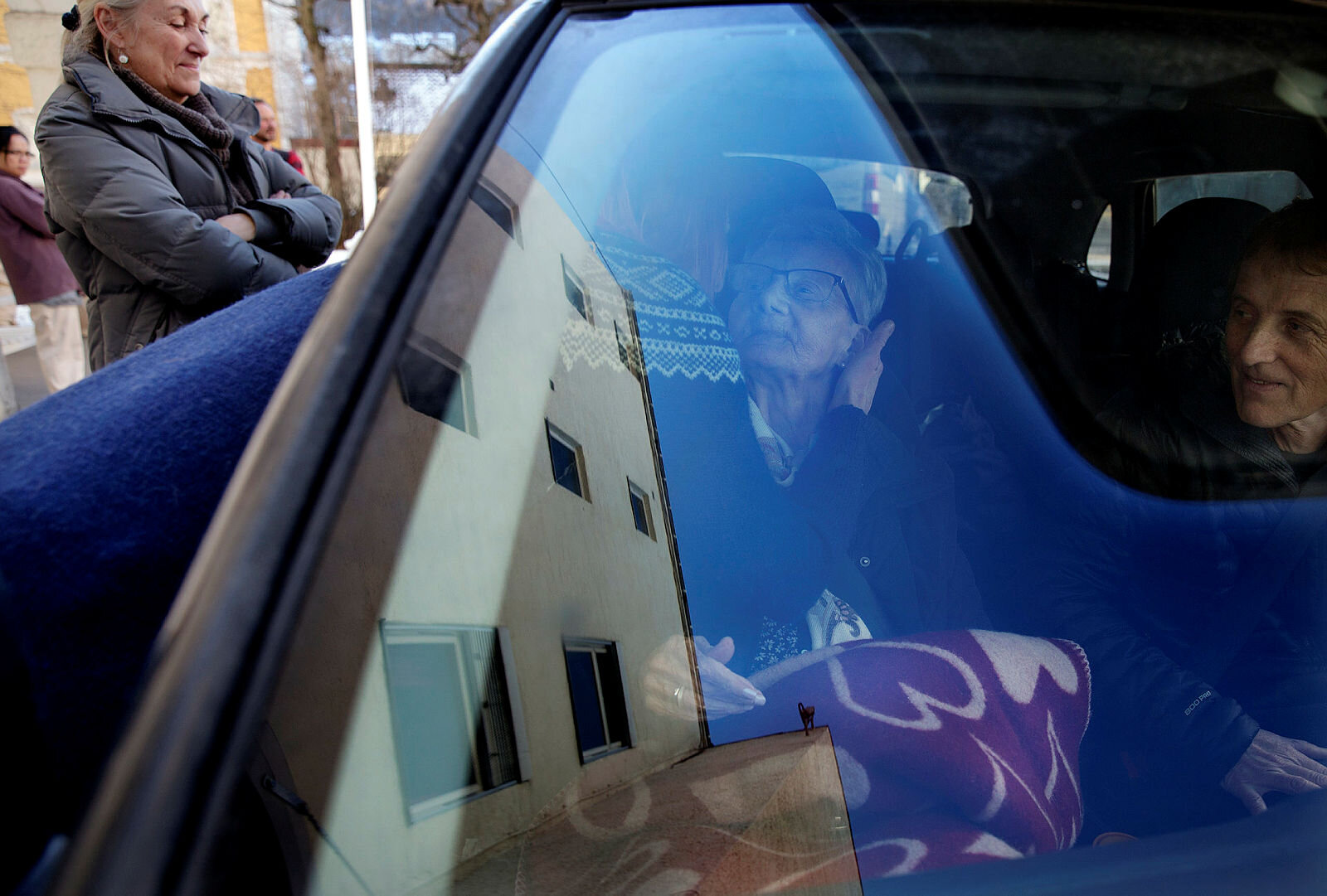 Bildet viser en eldre dame som sitter i en bil og som får klem av en yngre dame.