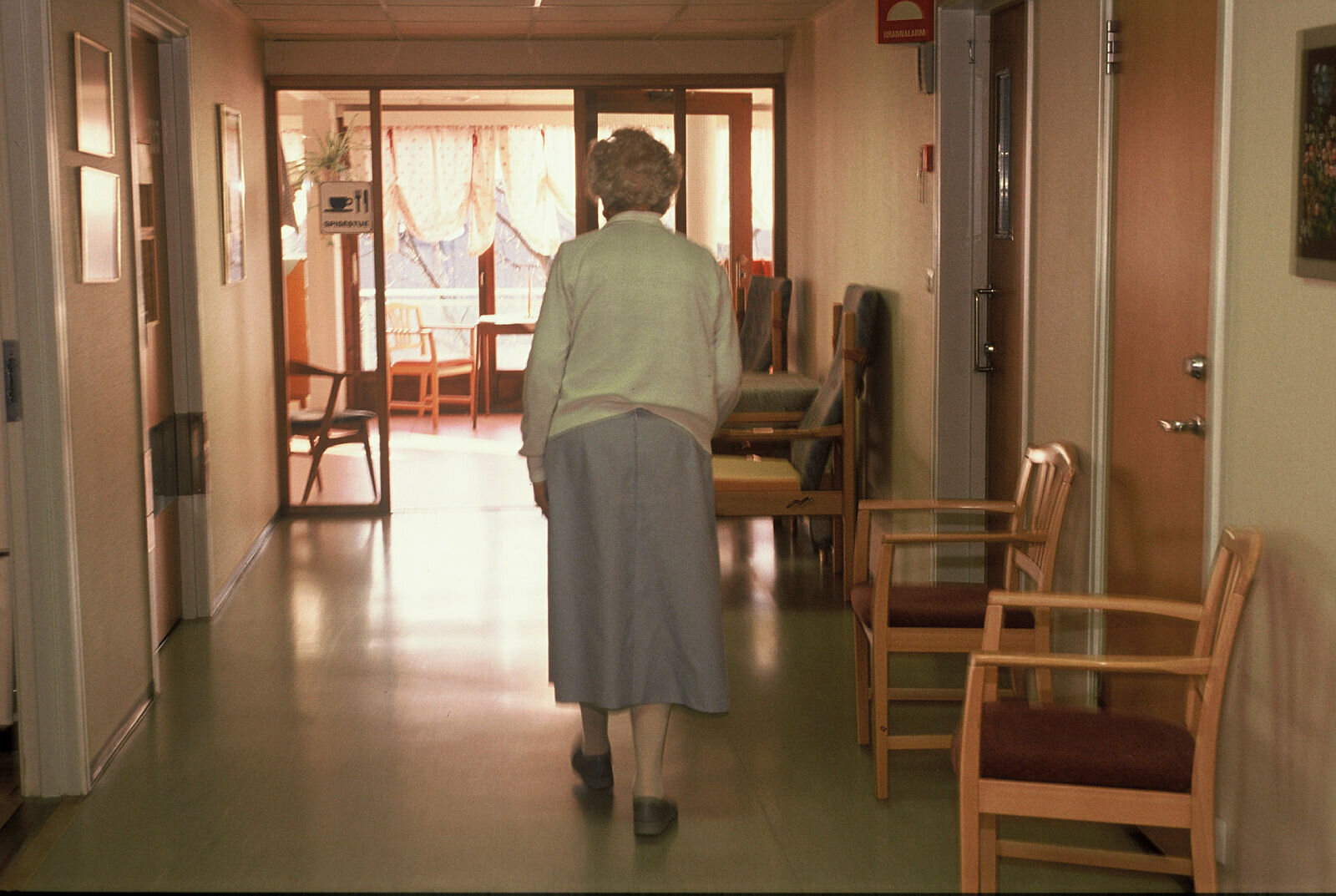 Eldre kvinne går nedover sykehjemskorridor Eldre kvinne går nedover sykehjemskorridor