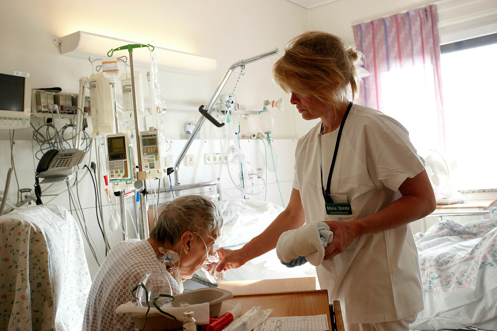 Pleie Sykepleier gir pasient noe å drikke