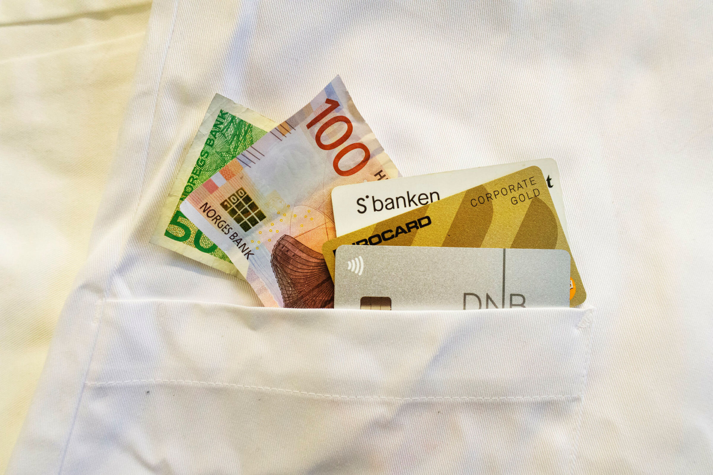 Penger og bankkort i lommen på en sykepleieruniform
