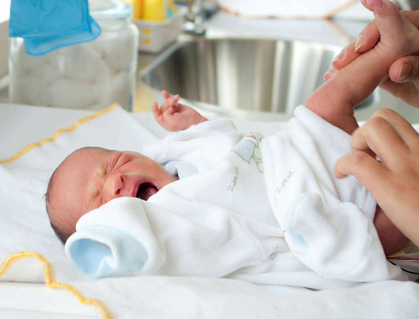 Gråtende baby Bildet viser en nyfødt baby som gråter idet hen får skiftet bleie