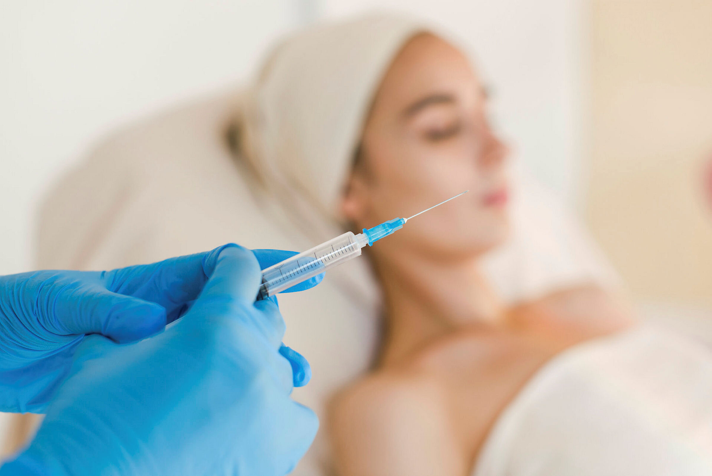 Botox Botox-sprøyte klargjøres i forgrunnen for pasient i bakgrunnen.