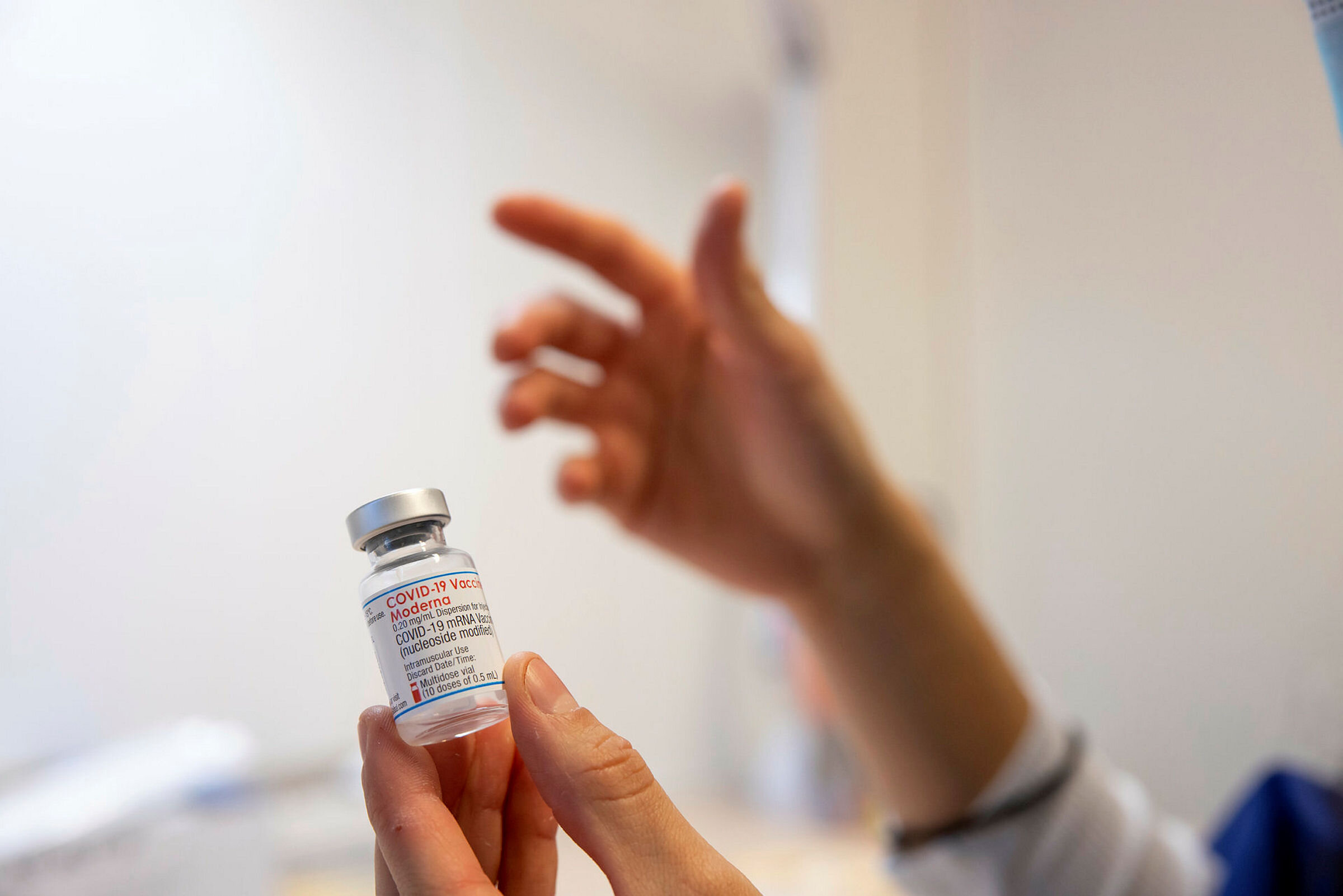Koronavaksine Bildet viser hender som holder et hetteglass med vaksine.