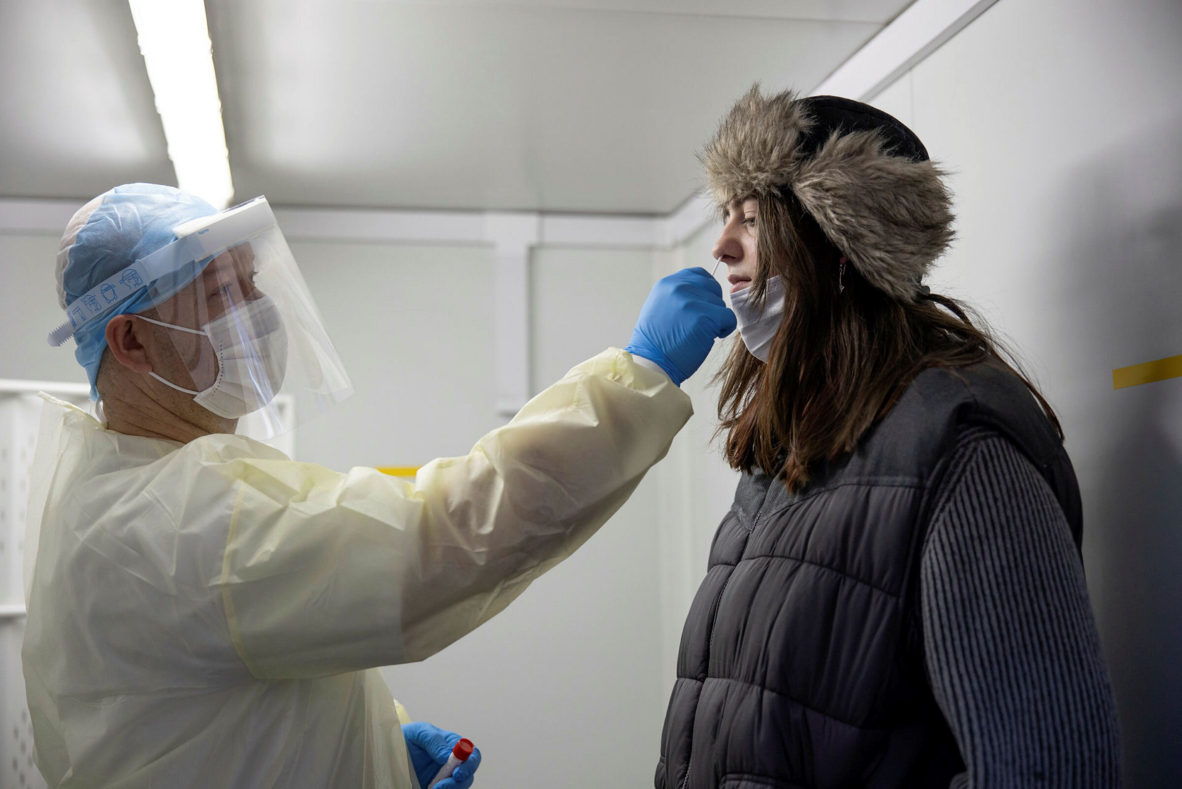 Bildet viser testpersonell som stikker en testpinne opp i nesen på en kvinne. Bildet viser testpersonell som stikker en testpinne opp i nesen på en kvinne.
