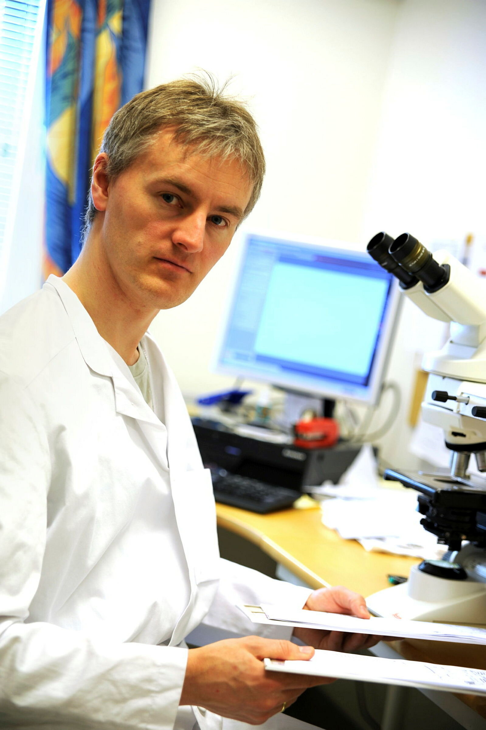 Bildet viser Sveinung Wergeland Sørbye ved mikroskopet.