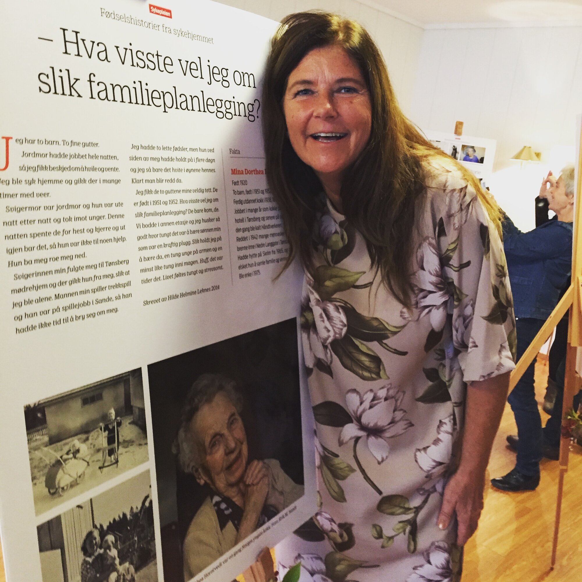 Hilde Helmine Leknes, fødselshistorier, Marie Treschow sykehjem Bildet viser Hilde Helmine Leknes som holder rundt en av historiene som er stilt ut, plakat på staffeli.