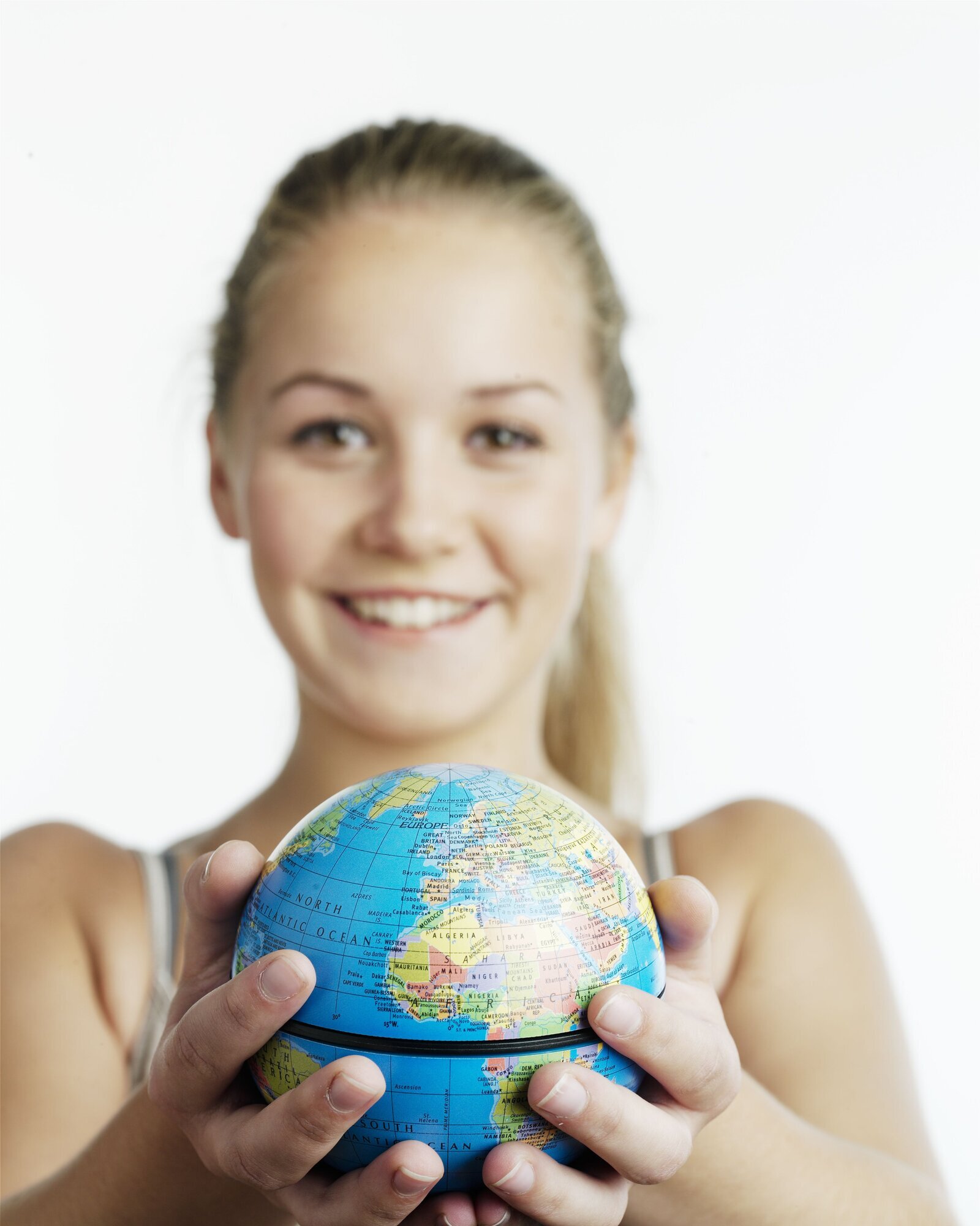 Mange unge reiser ut av Norge for å utdanne seg til sykepleier. Det kan være et sjansespill. Ikke alle får norsk autorisasjon når de kommer tilbake. Bilde av en smilende kvinne som holder en jordklode mellom hendene