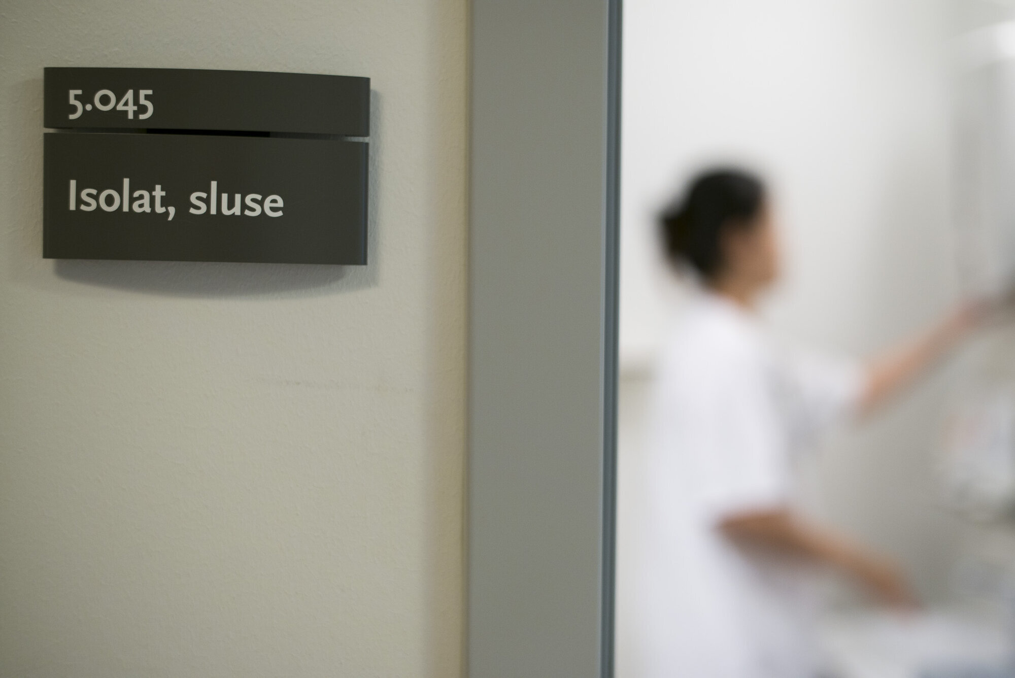 Antibiotikaresistens, hygiene, smittevern Bildet viser en dør inn til en sluse til et isolat og en sykepleier kan skimtes.