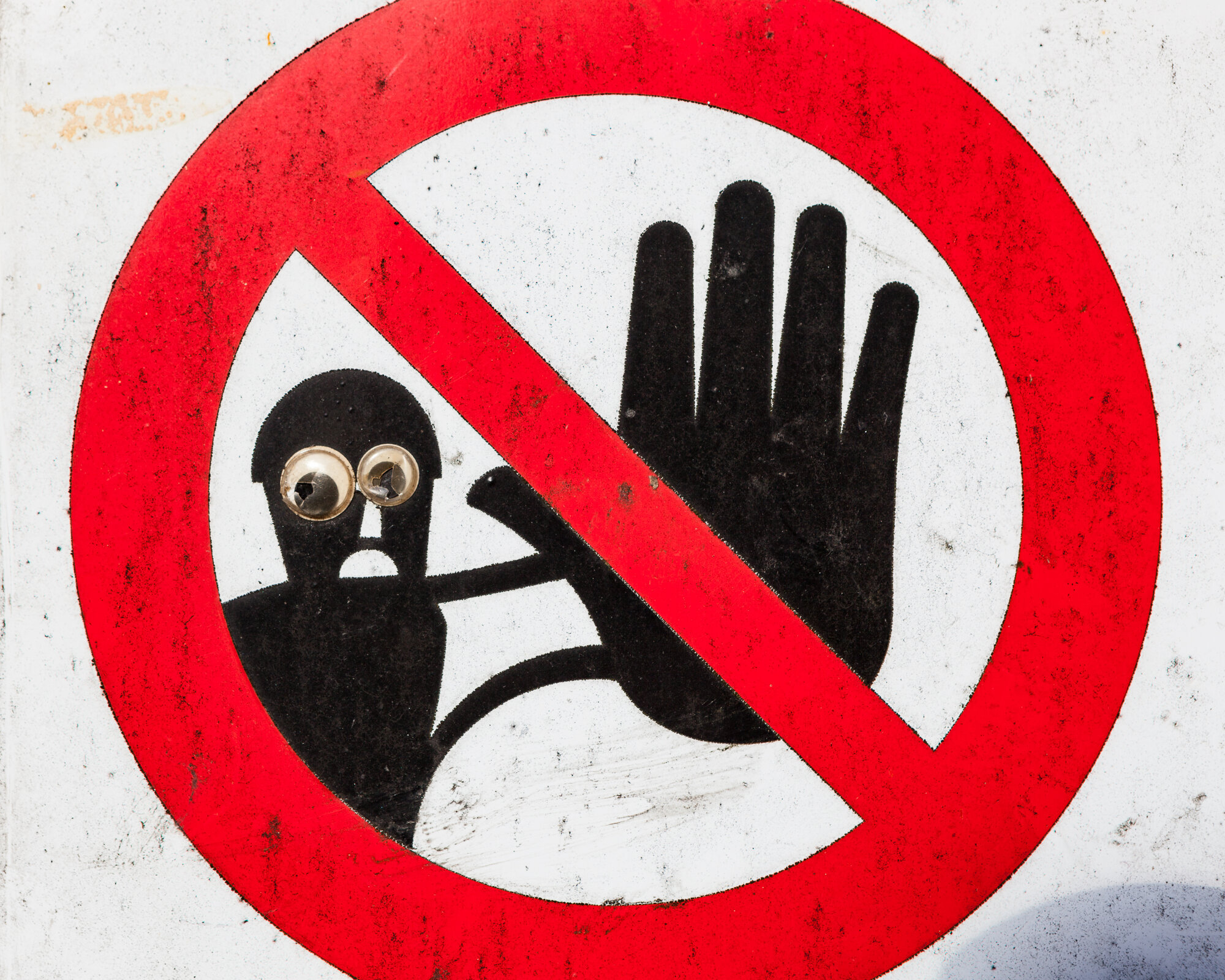 Forbudsskilt Bildet viser et forbudsskilt. En svart skikkelse i bakgrunnen viser stoppsignalet med håndflaten