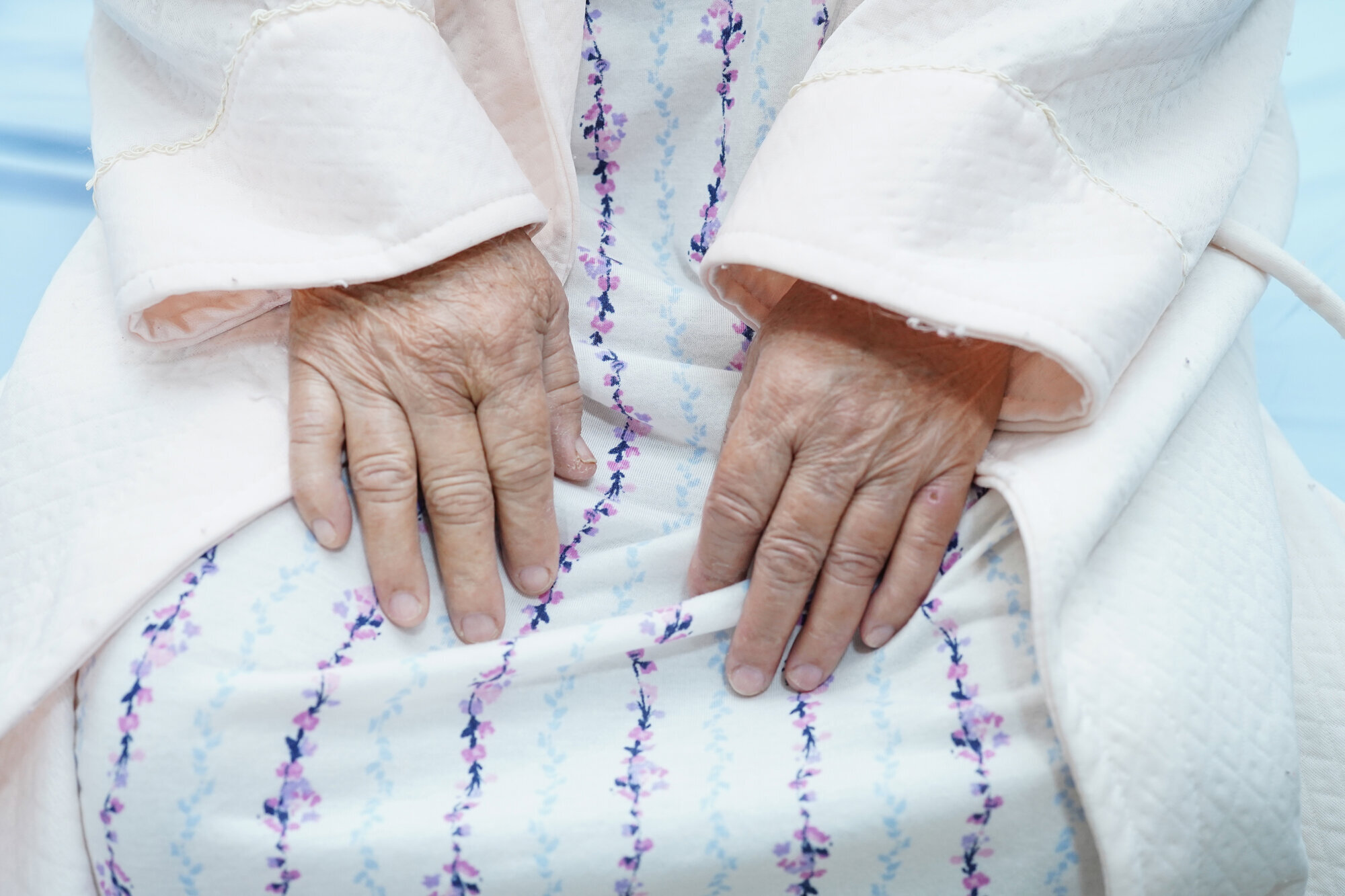 En eldre kvinne på sykehus. En eldre kvinne sitter på en sykehusseng.