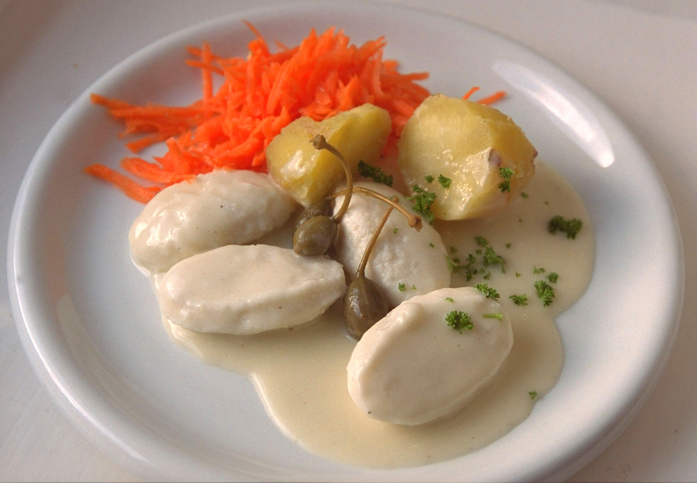 Fiskeboller, hvit saus Bildet viser fiskeboller i hvit saus på en tallerken.