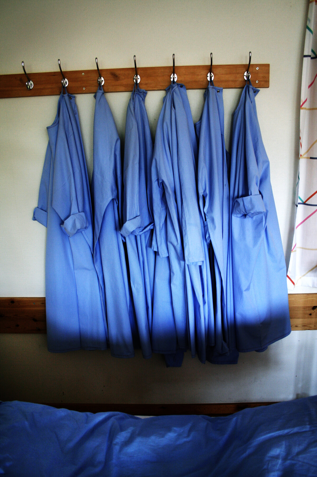 stellefrakk, stell, beskyttelse Bildet viser en knaggrekke der det henger flere blå stellefrakker.