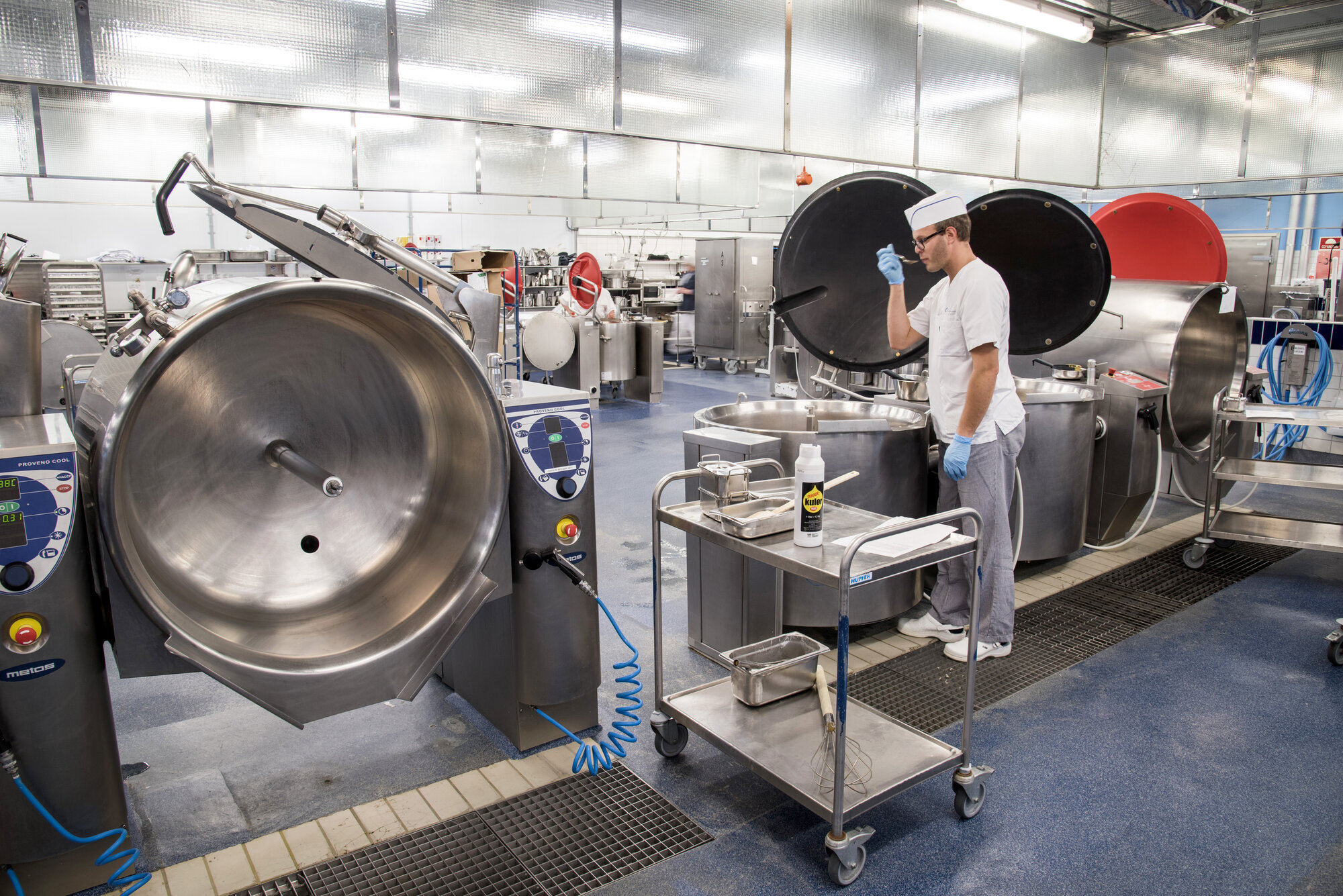 Mat Fra storkjøkken der en av kokkene smaker på maten