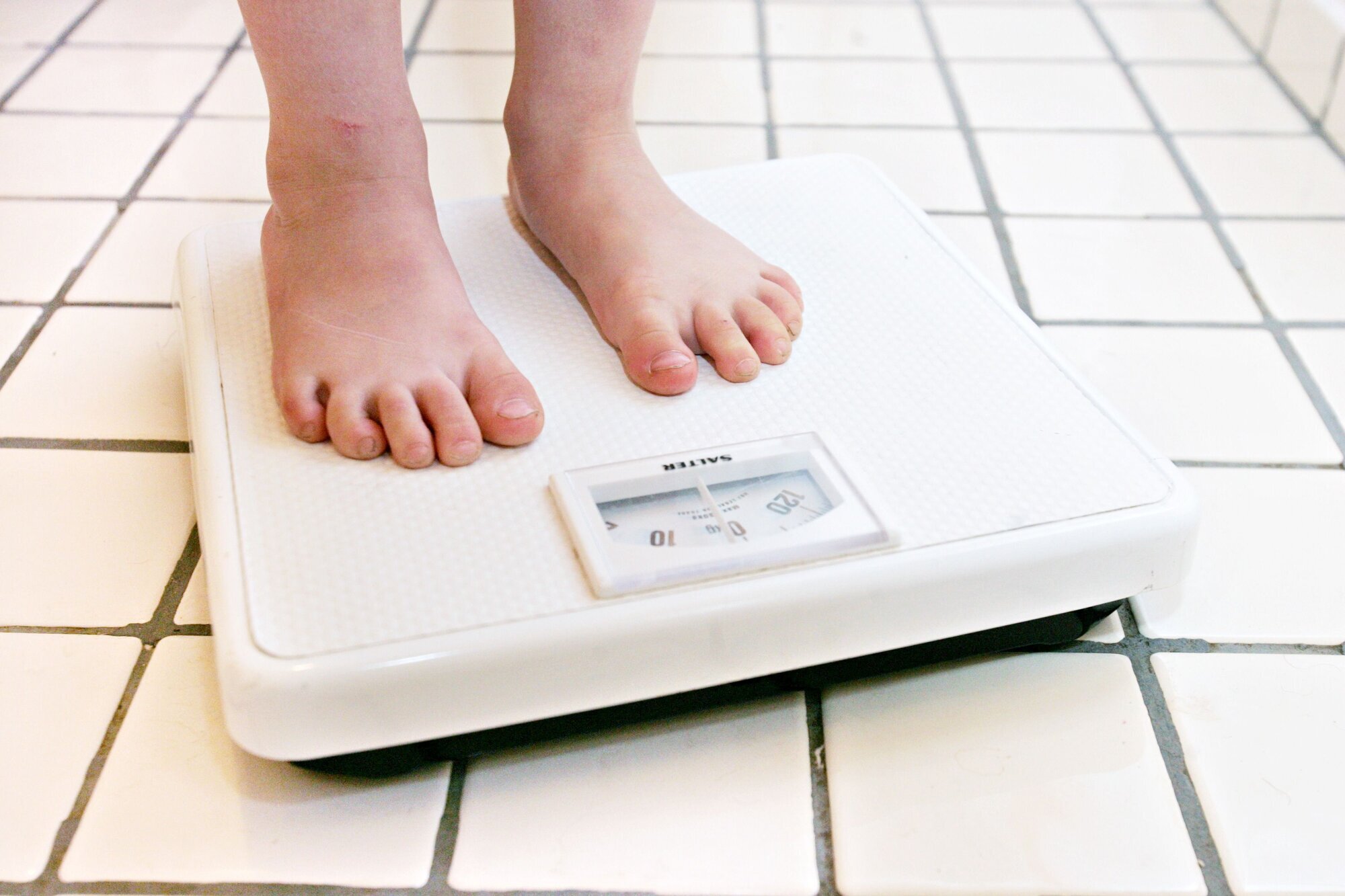 Barn som veier seg Bildet viser barneføtter på en vekt.