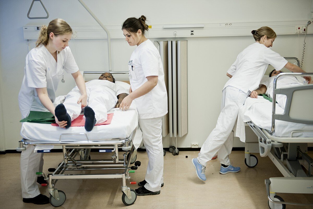 Sykepleiestudenter øver ved seng. Sykepleiestudenter som øver ved seng.