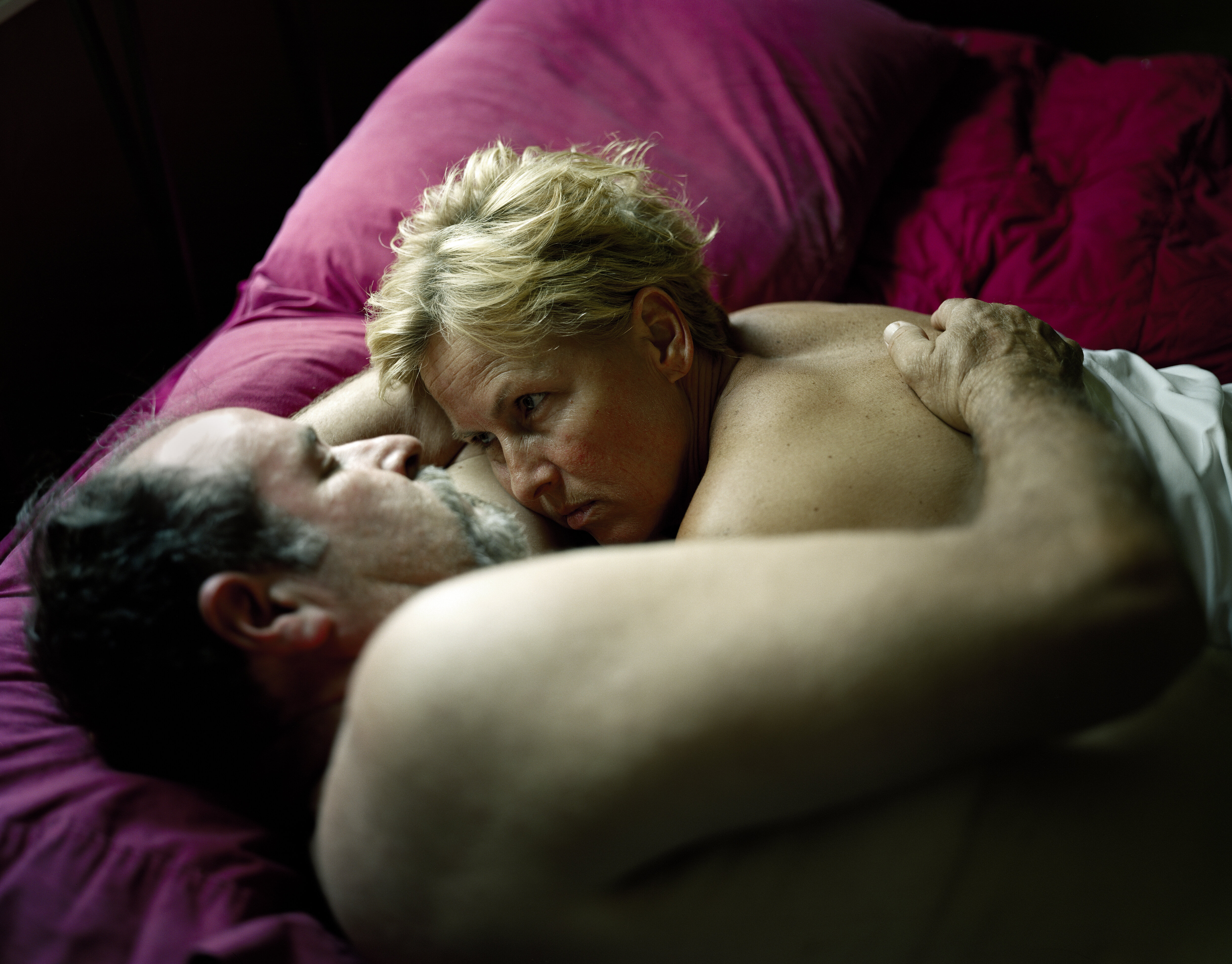 Seksualitet, hjerteinfarkt, rådgivning Et voksent par ligger i sengen halvveis under dyna og ser på hverandre