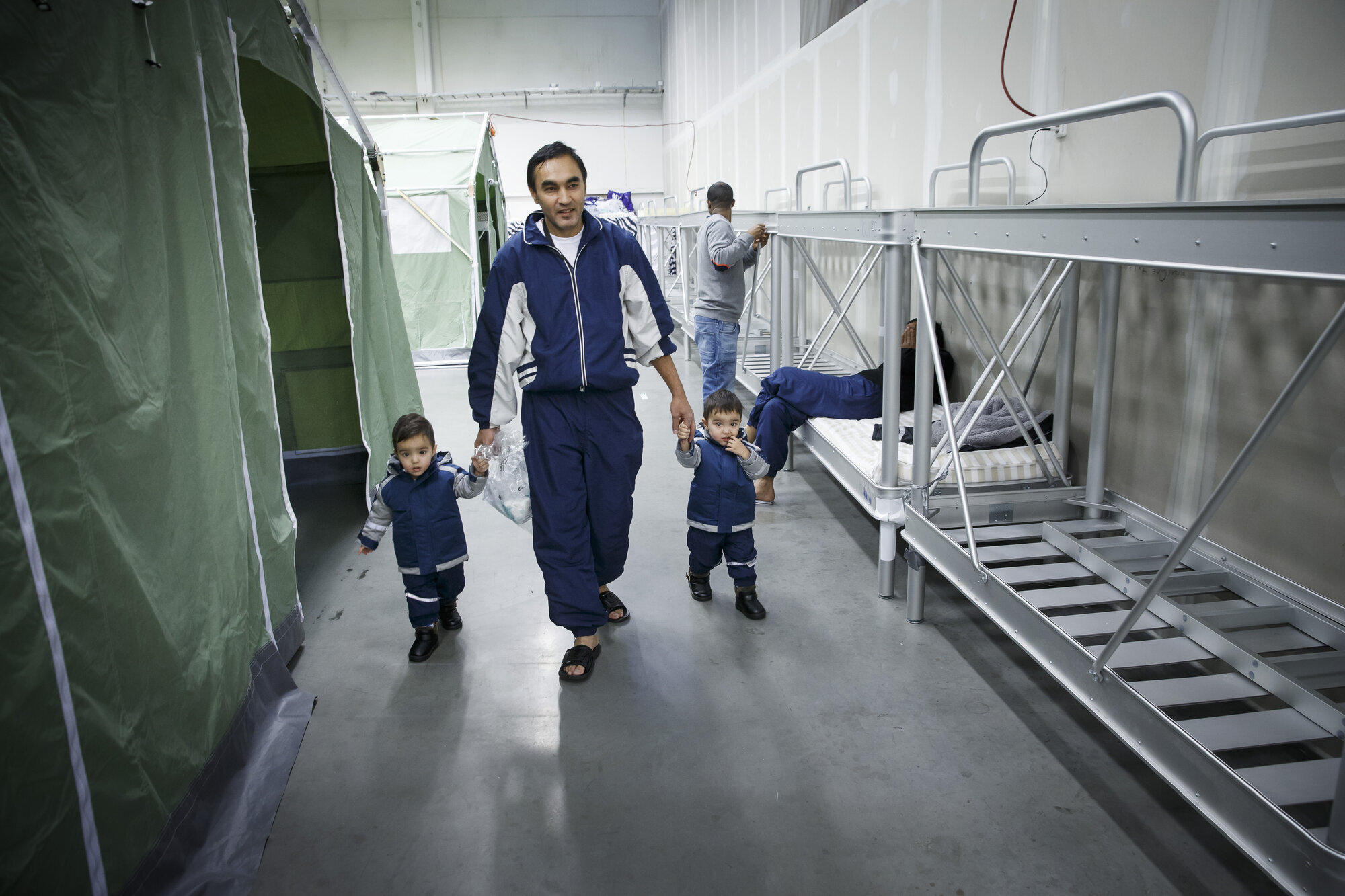 flyktninger, ankomstmottak, Råde Bildet viser Gulam Sarwar og tvillingsønnene som går langs en rad med køyesenger på ankomstmottaket i Råde.