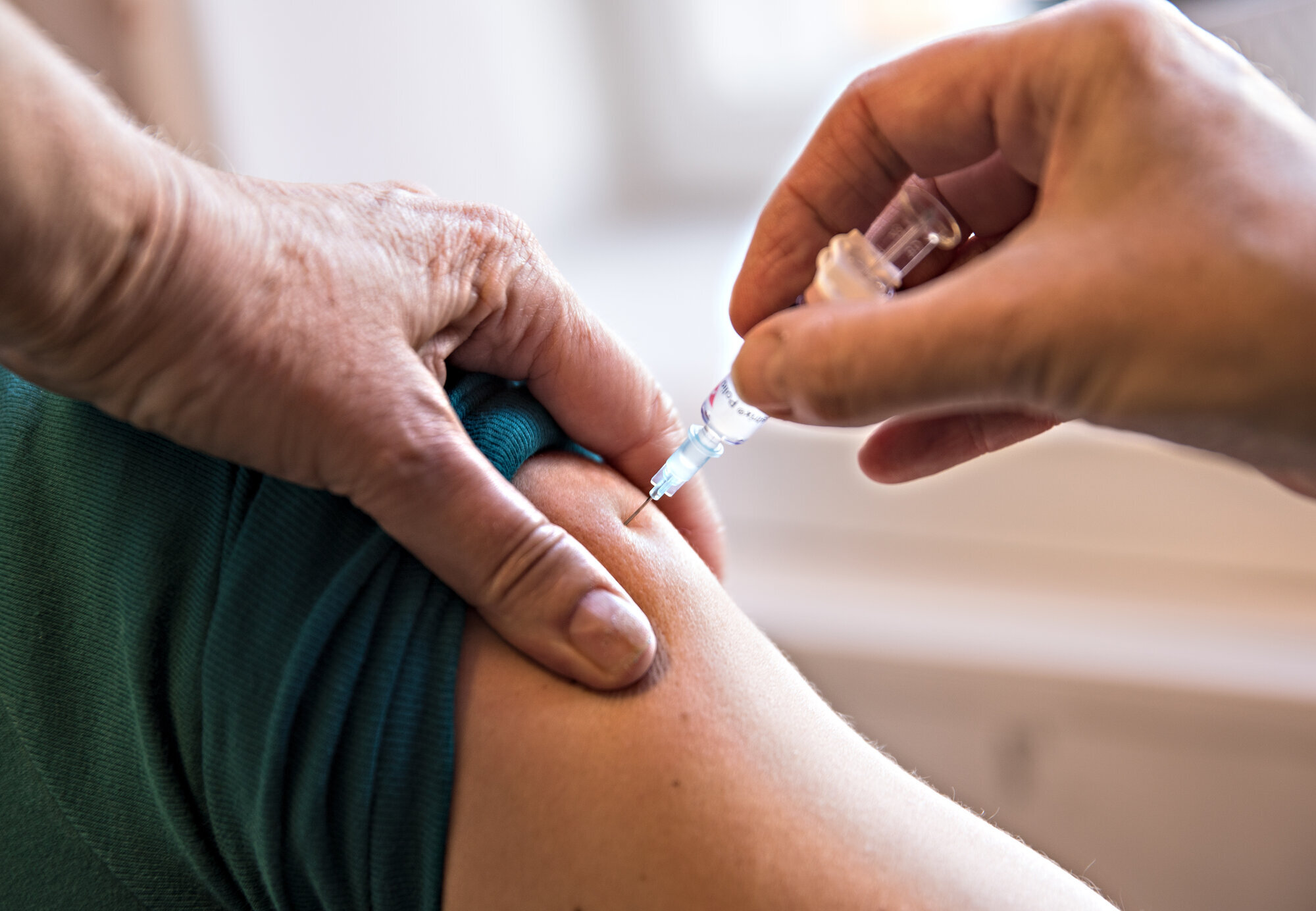 Bildet viser en helsesøster ved et vaksinasjonskontor som setter en vaksine Vaksinering