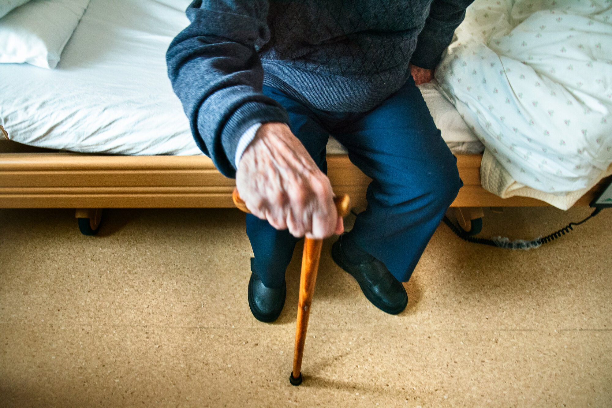 På sykehjem Bildet viser hånden til en gammel mann som støtter seg til en stokk.